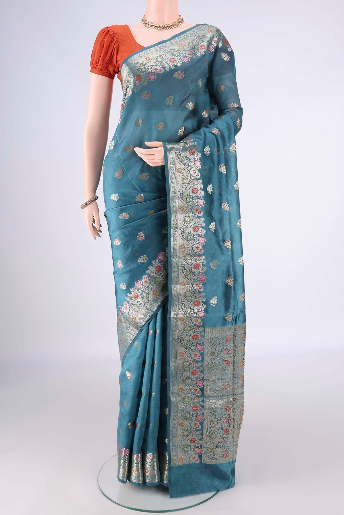 Pure Silk Maya Blue Banarasi Raw Saree with Zari Butta on the body and Zari Border.  displayed on a mannequin
