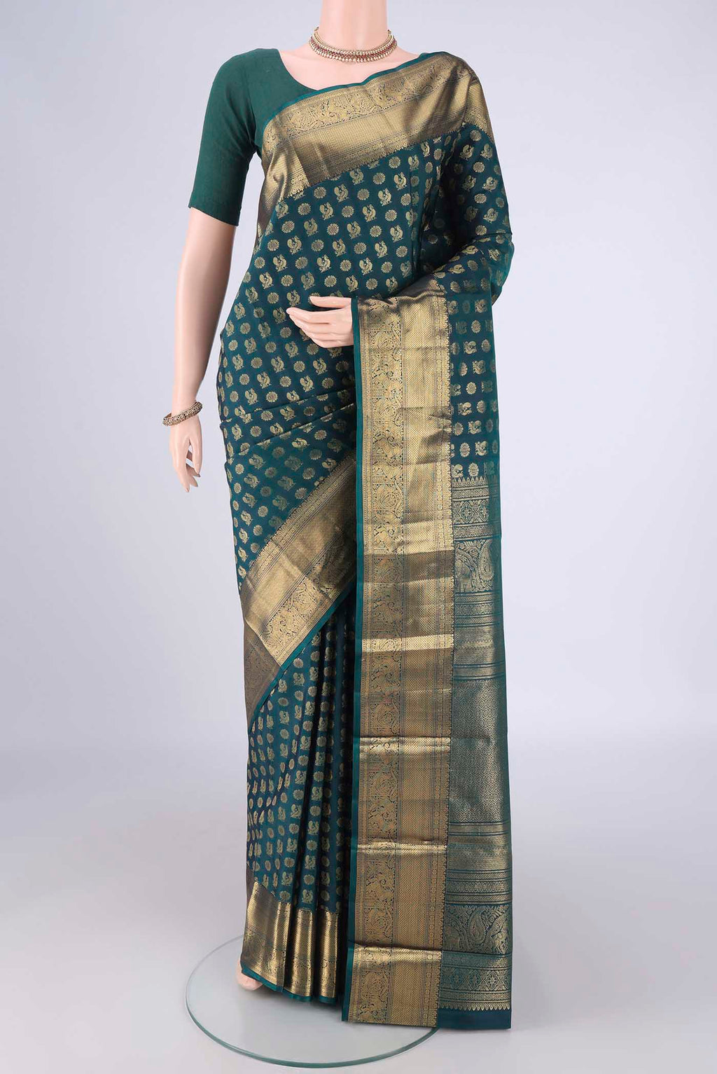 Bottle Green Kanchipuram Silk Saree with Zari Butta on the body and Zari Border.  displayed on a mannequin