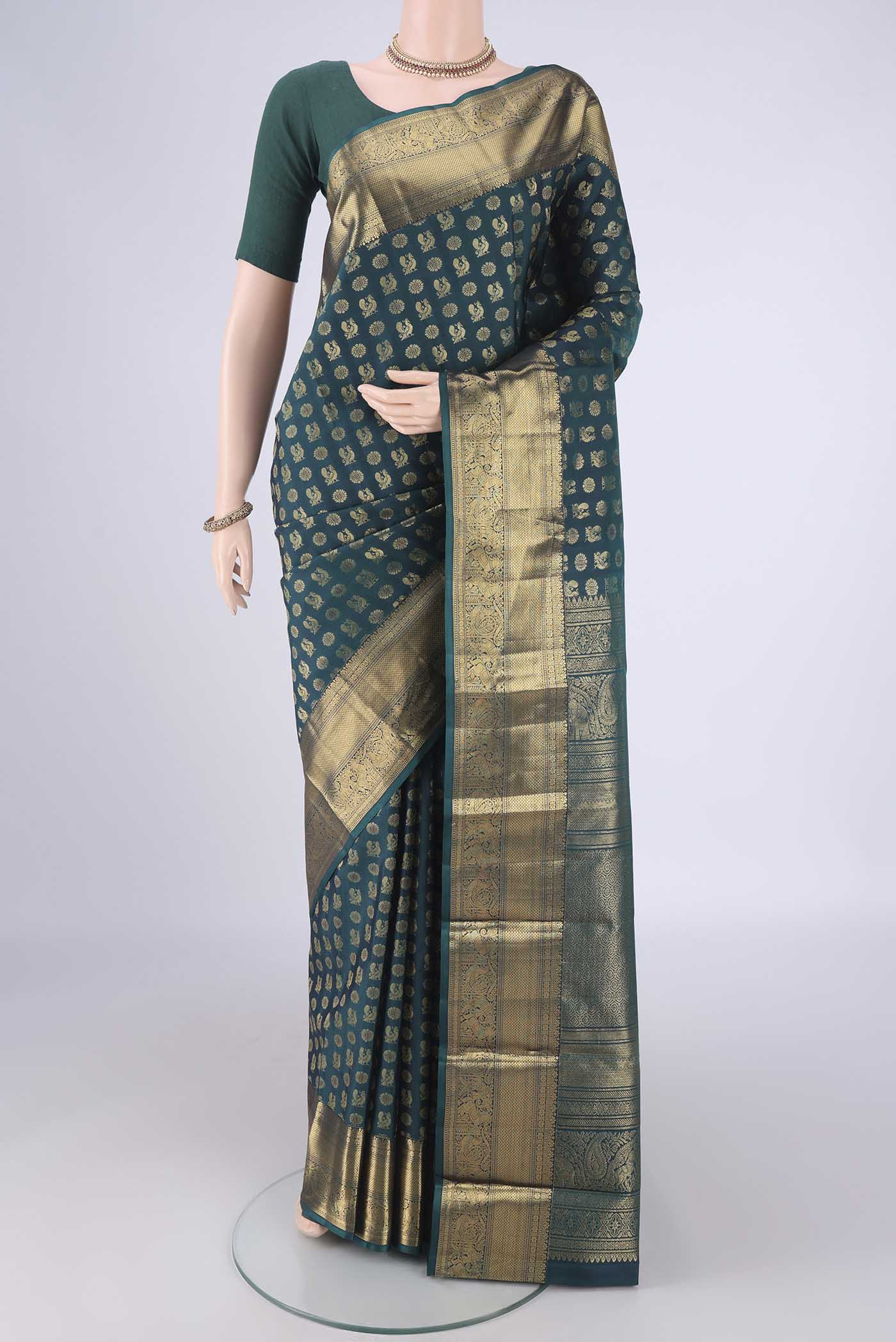 Bottle Green Kanchipuram Silk Saree with Zari Butta on the body and Zari Border.  displayed on a mannequin