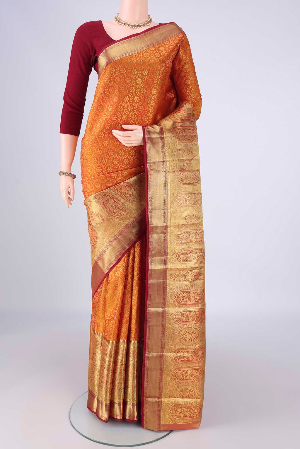 Brick Orange Kanjivaram Silk Saree with Zari Brocade on the body and Zari Border.  displayed on a mannequin