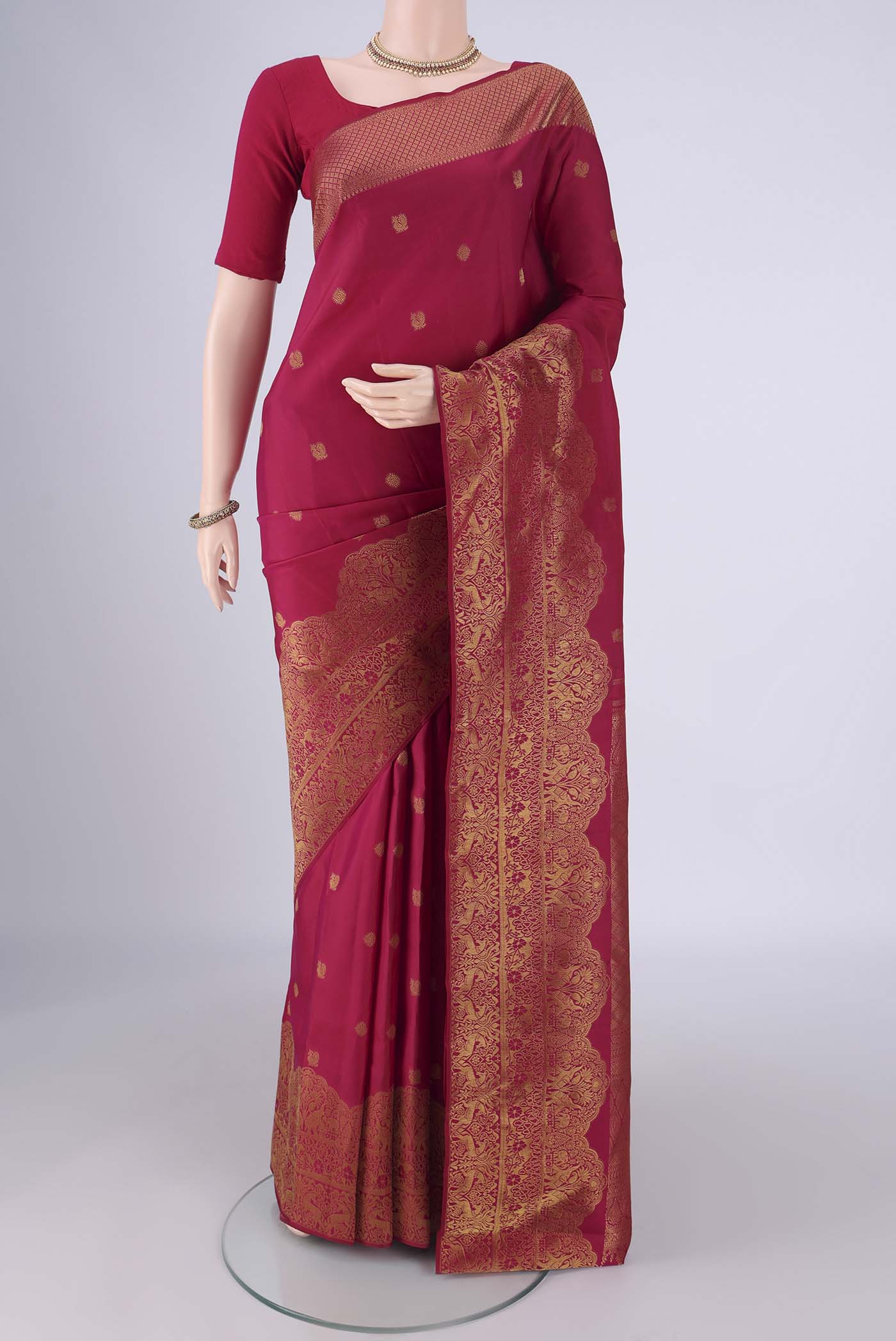 Maroon Kanchipuram Silk Saree with Zari Butta on the body and Zari Border.  displayed on a mannequin