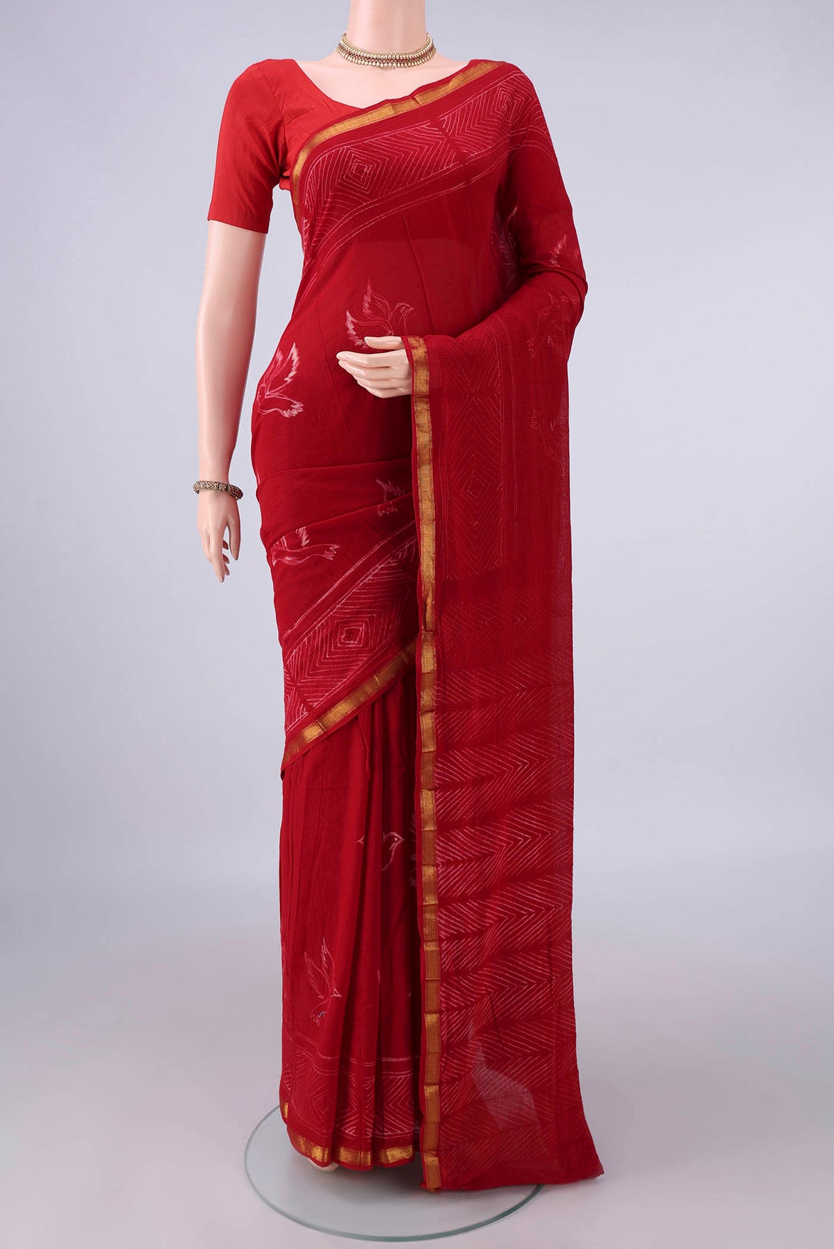 Red Cotton Saree with Printed design on the body and Zari Border.  displayed on a mannequin