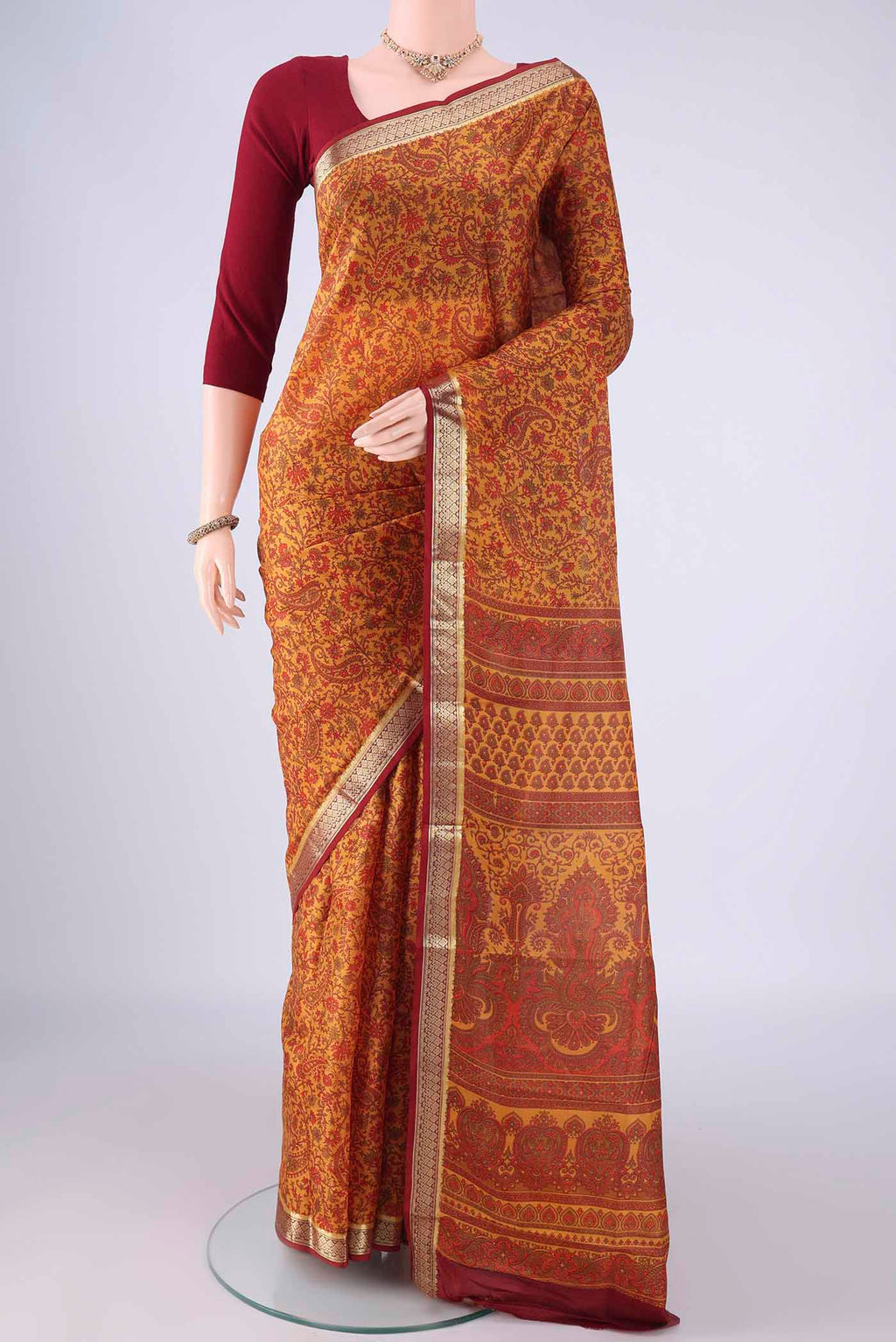 Mustard Printed Silk Saree with Printed design on the body and Zari Border.  displayed on a mannequin