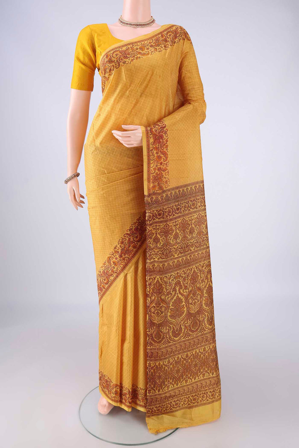 Mustard Printed Silk Saree with Printed design on the body and Printed Border.  displayed on a mannequin
