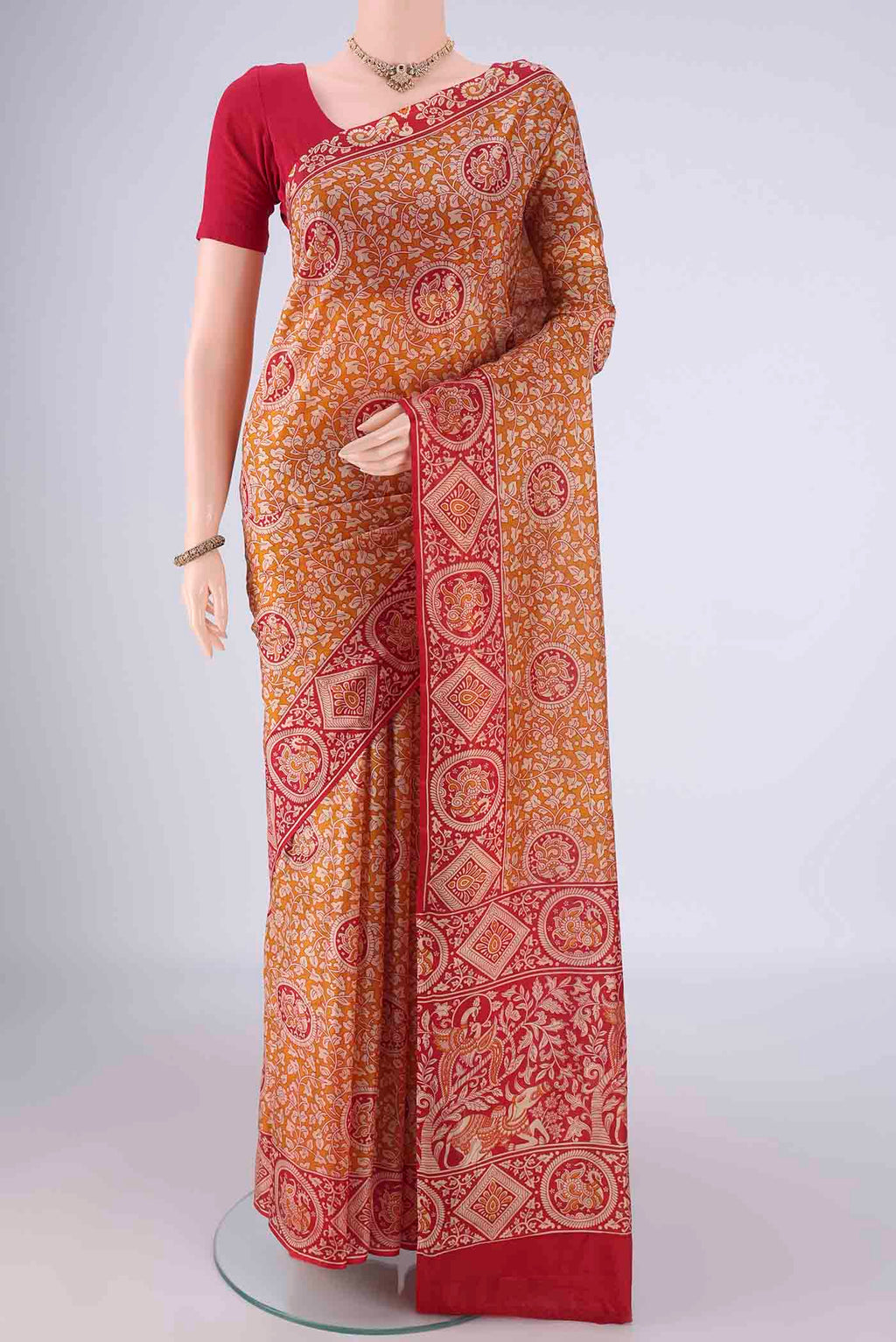 Rust Printed Silk Saree with Printed design on the body and Zari Border.  displayed on a mannequin