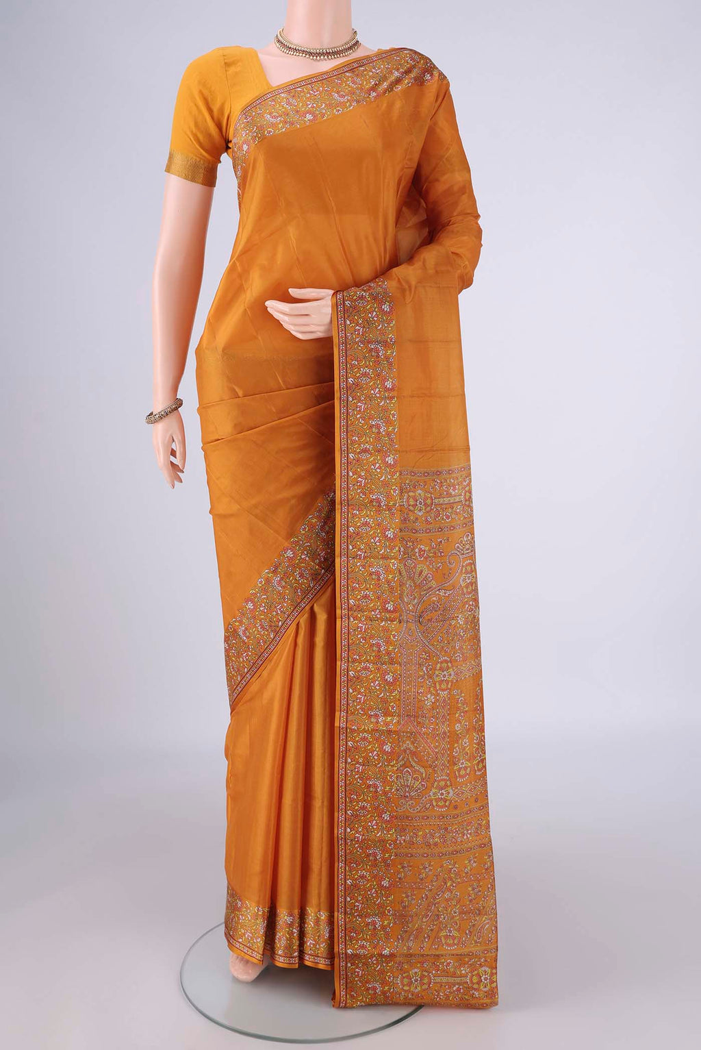 Mustard Printed Silk Saree with Plain Body and Printed Border.  displayed on a mannequin