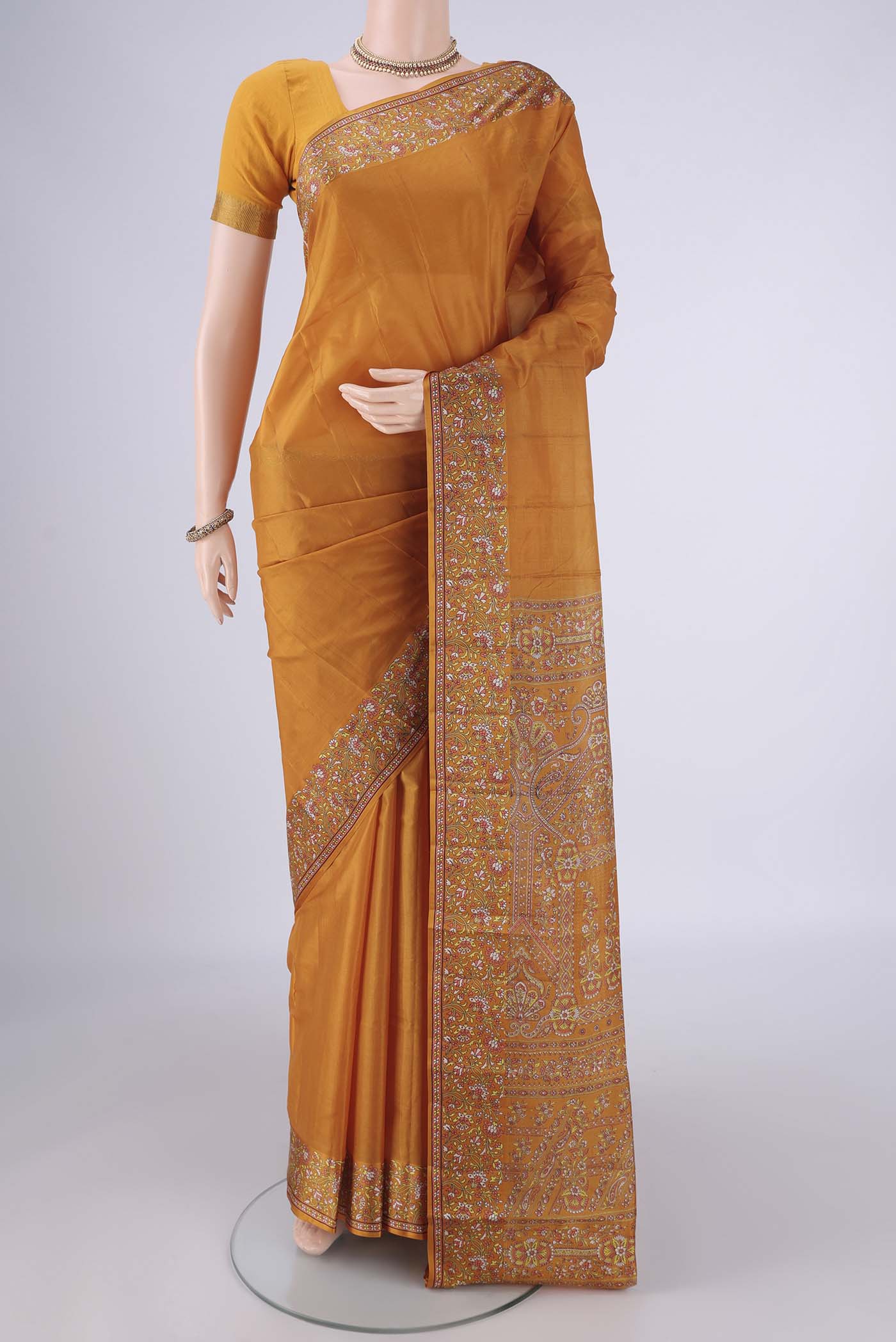 Mustard Printed Silk Saree with Plain Body and Printed Border.  displayed on a mannequin