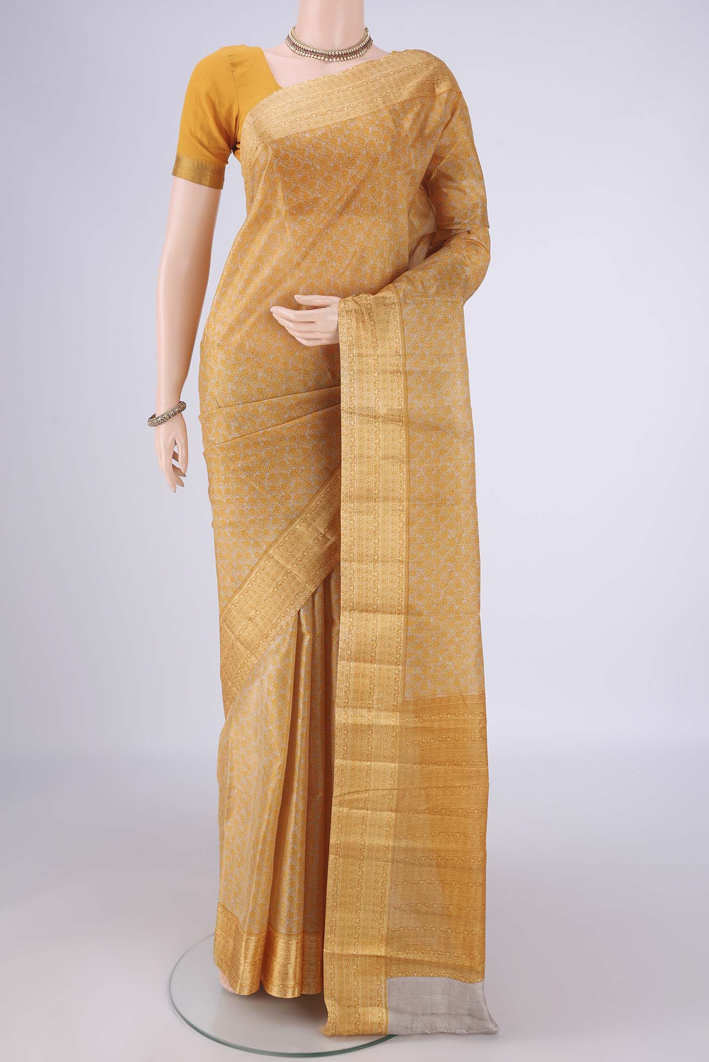 Beige Printed Silk Saree with Printed design on the body and Zari Border.  displayed on a mannequin