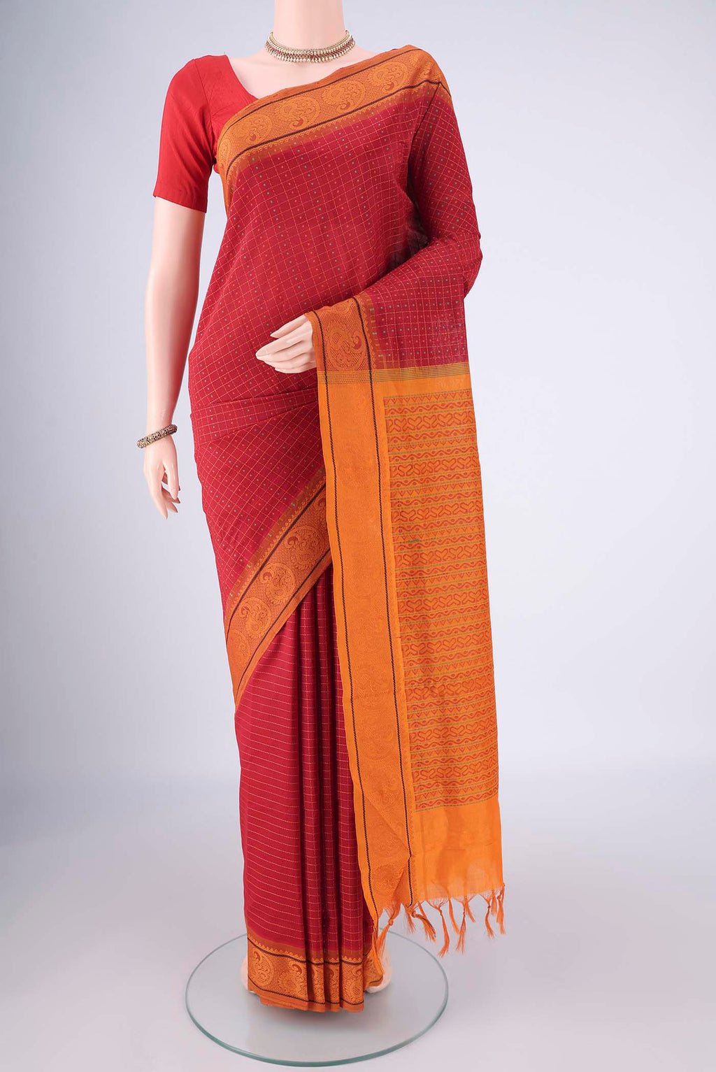 Red Blended Poly Cotton Saree with Checked design on the body and Thread Border.  displayed on a mannequin
