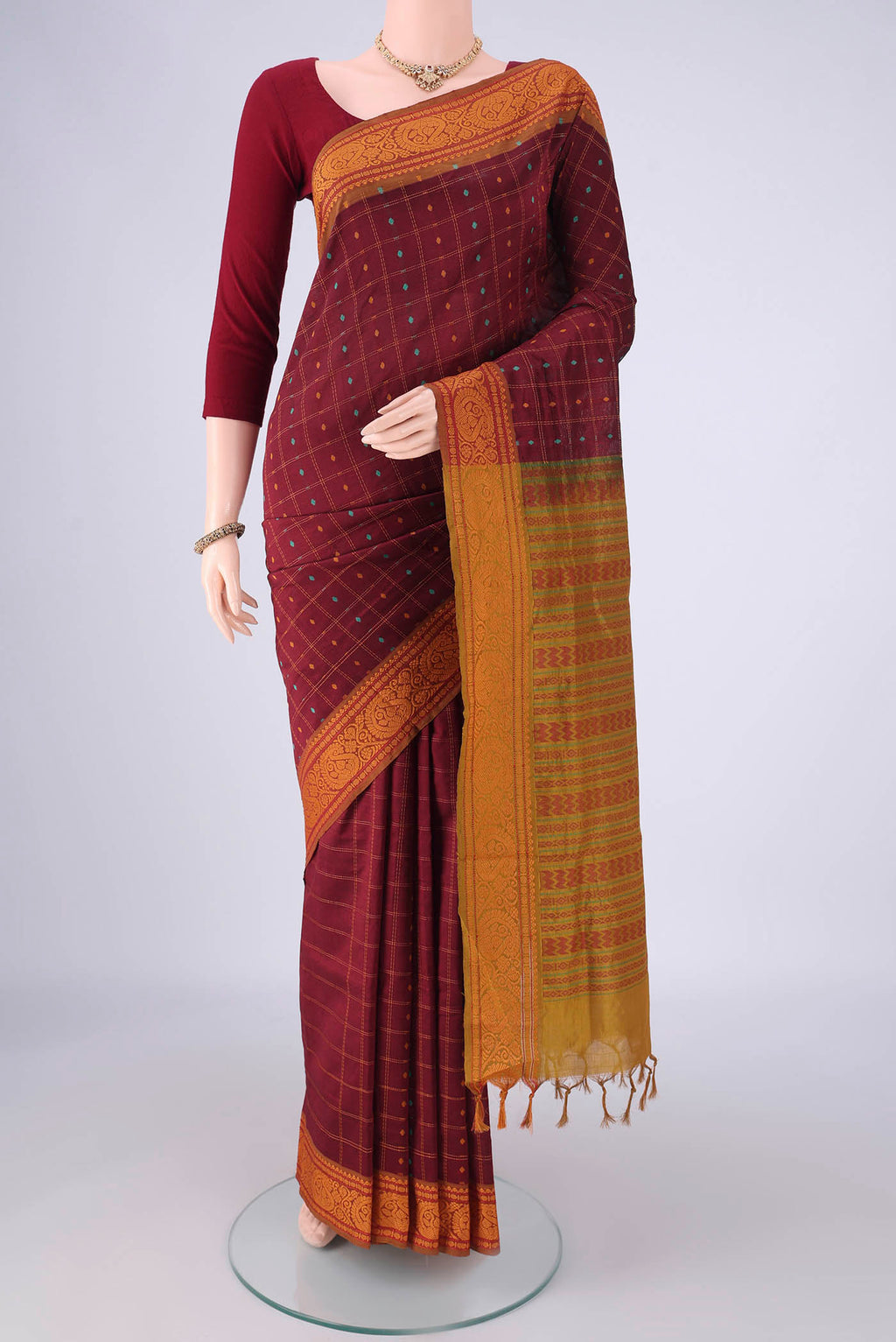 Maroon Blended Poly Cotton Saree with Checked design on the body and Thread Border.  displayed on a mannequin