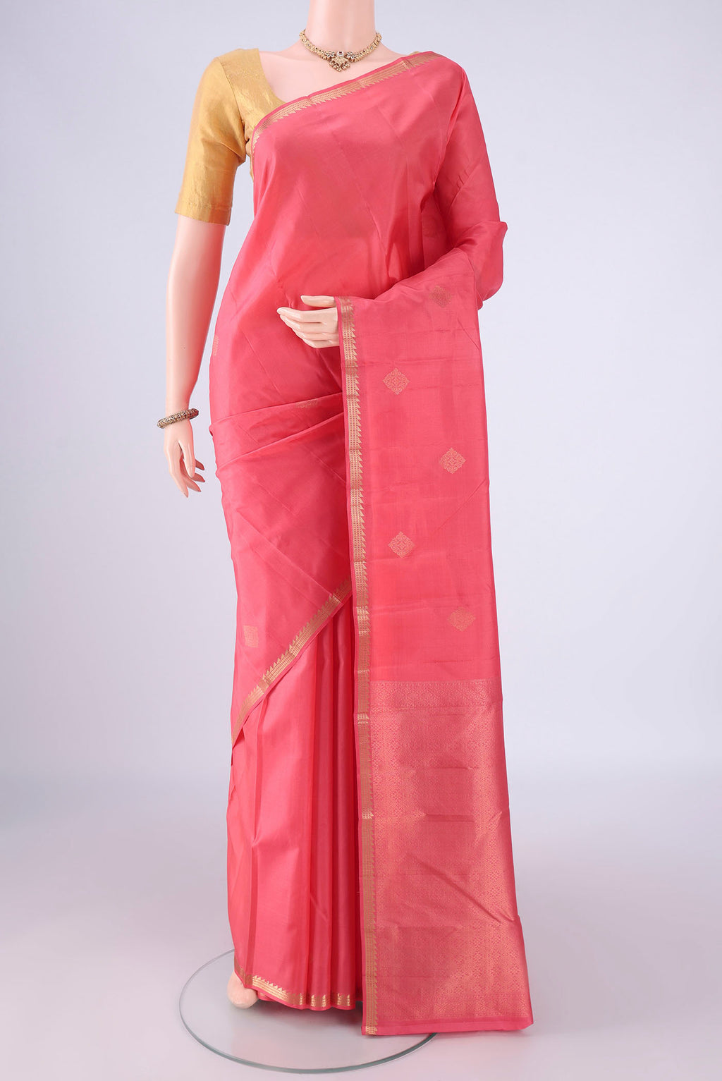 Coral Kanjivaram Silk Saree with Zari Butta on the body and Zari Border.  displayed on a mannequin