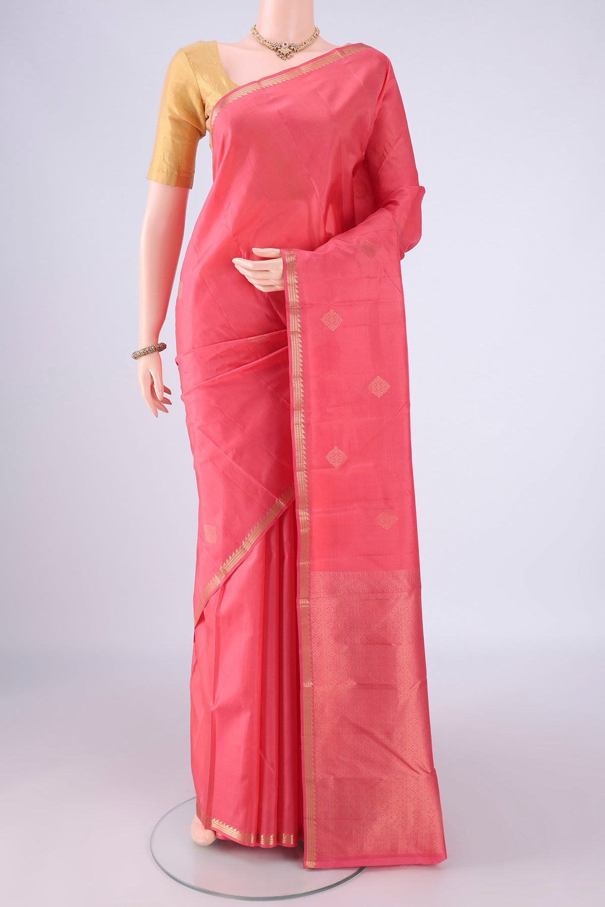 Coral Kanjivaram Silk Saree with Zari Butta on the body and Zari Border.  displayed on a mannequin