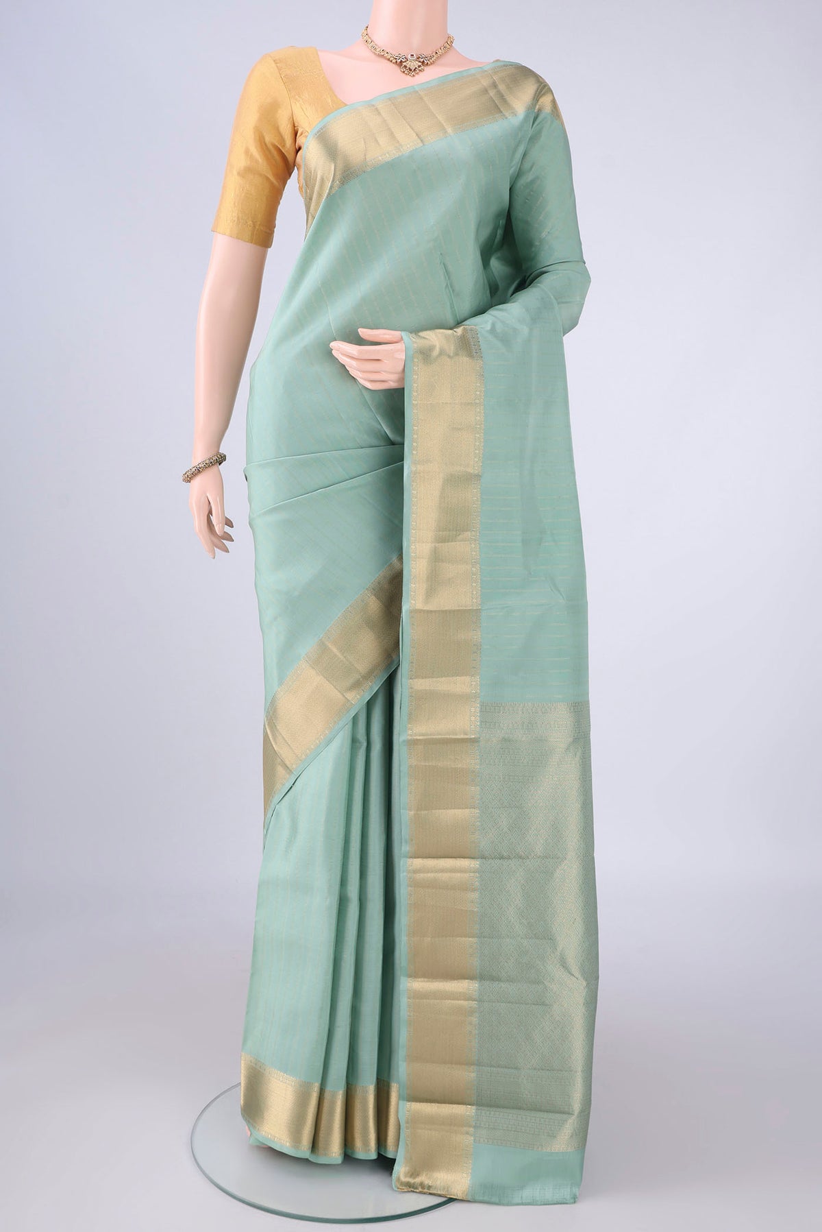 Pista Green Kanchipuram Silk Saree with Stripes on the body and Zari Border.  displayed on a mannequin