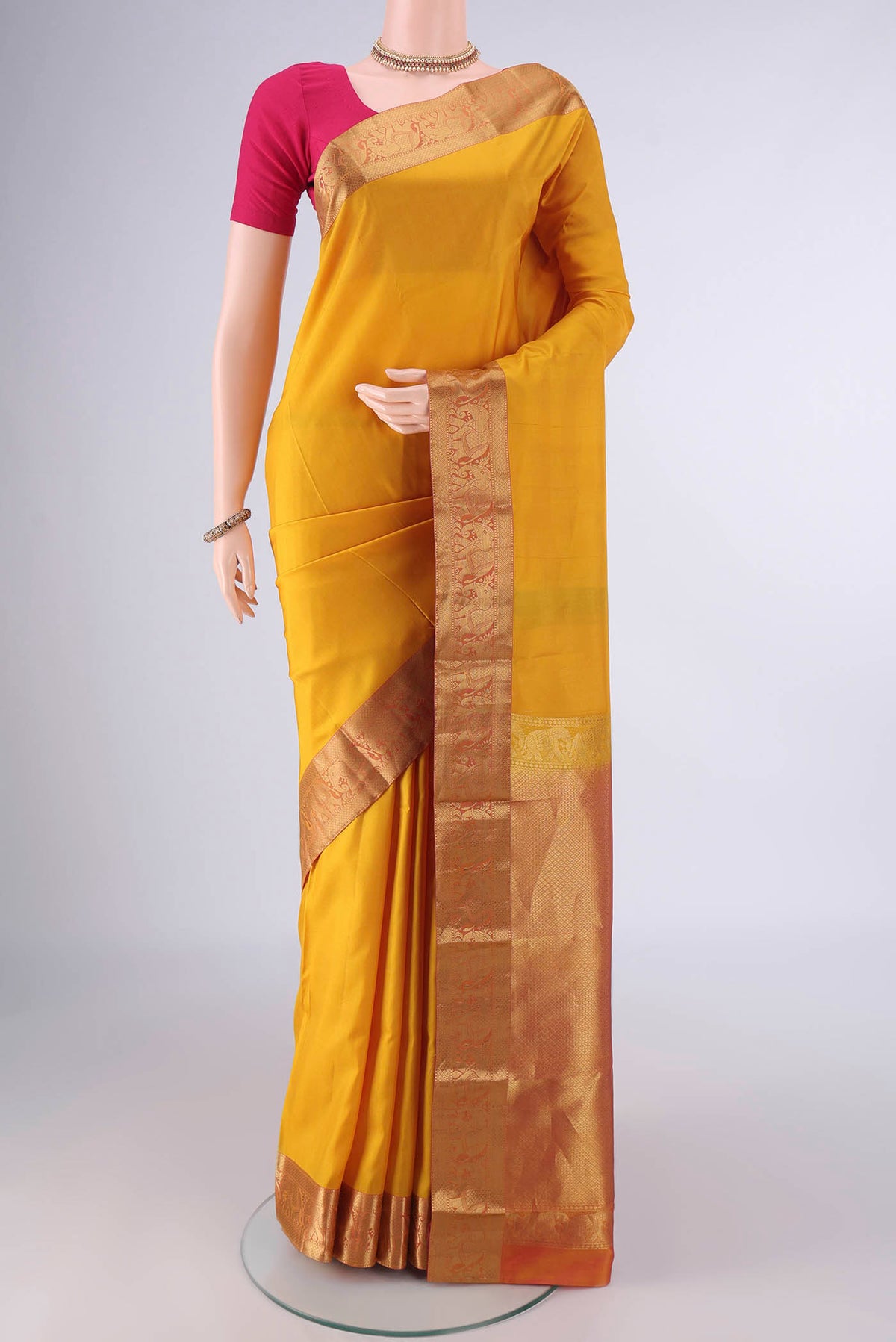 Pure Silk Mustard Kanjivaram Saree with Plain Body and Zari Border.  displayed on a mannequin
