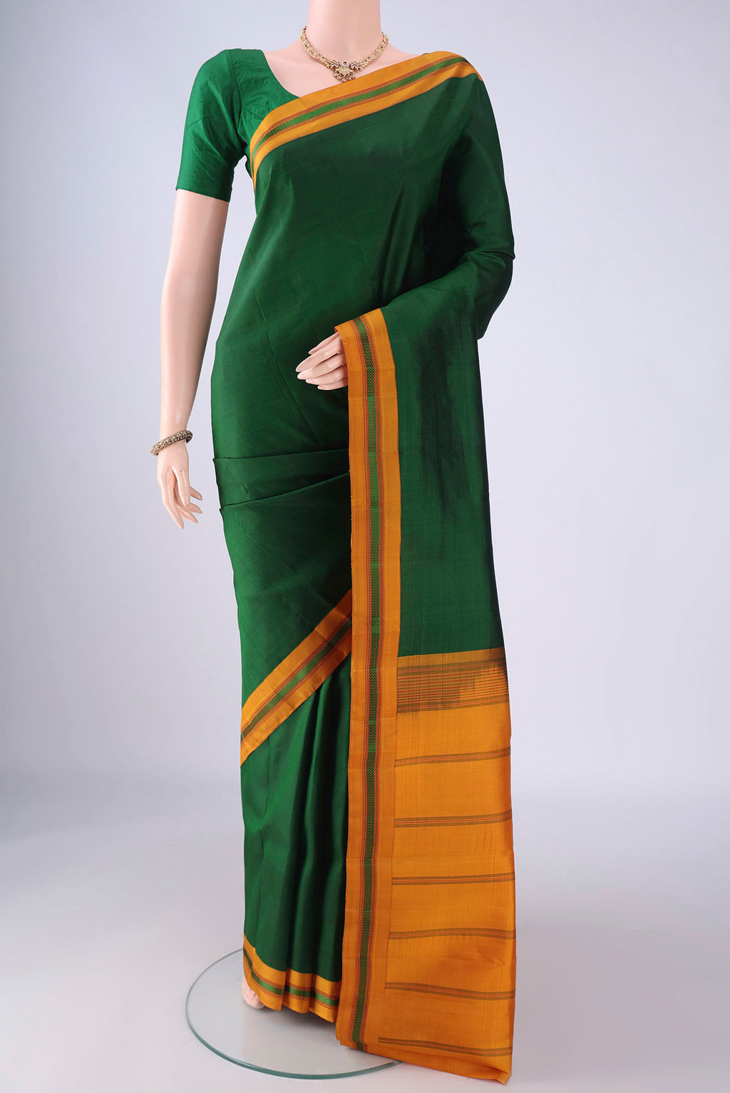 Bottle Green Kanjivaram Silk Saree with Plain Body and Thread Border.  displayed on a mannequin