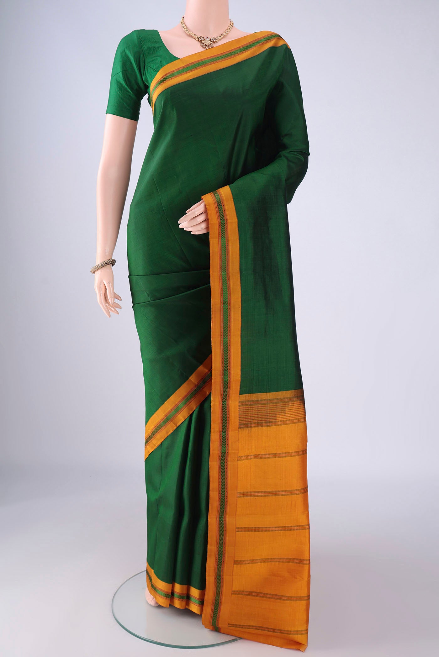 Bottle Green Kanjivaram Silk Saree with Plain Body and Thread Border.  displayed on a mannequin