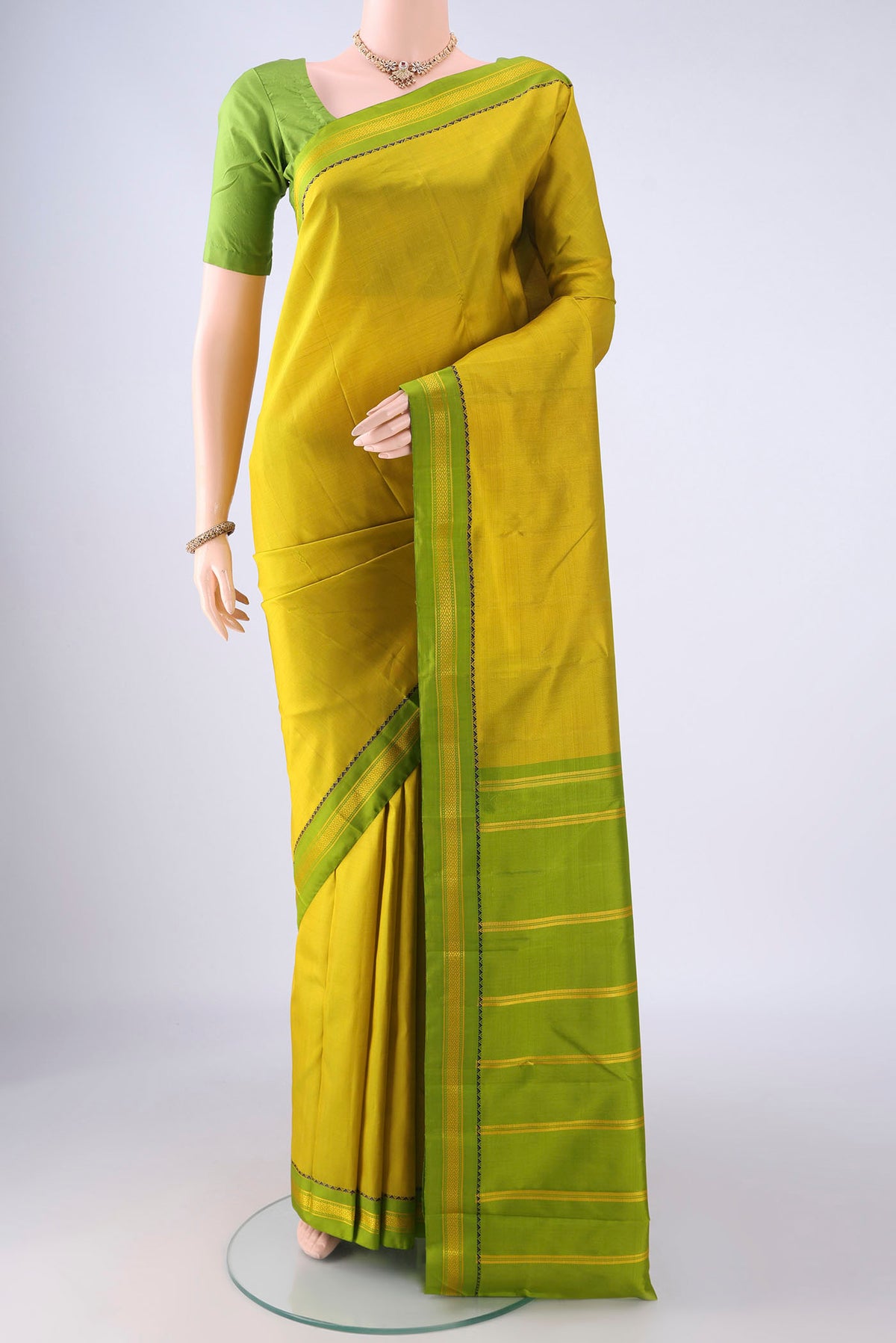Acid Green Kanjivaram Silk Saree with Plain Body and Thread Border.  displayed on a mannequin