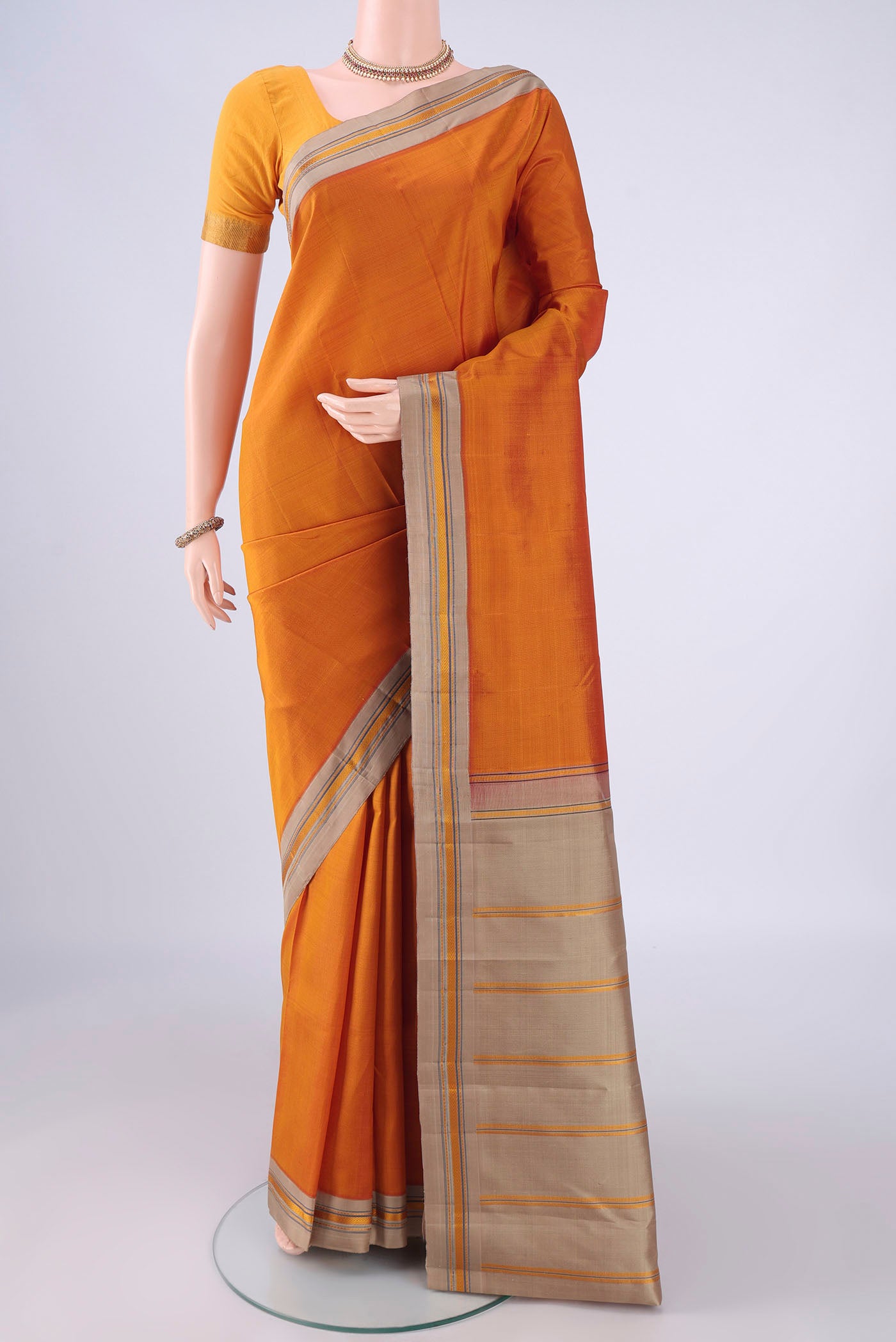 Mustard Kanjivaram Silk Saree with Plain Body and Thread Border.  displayed on a mannequin