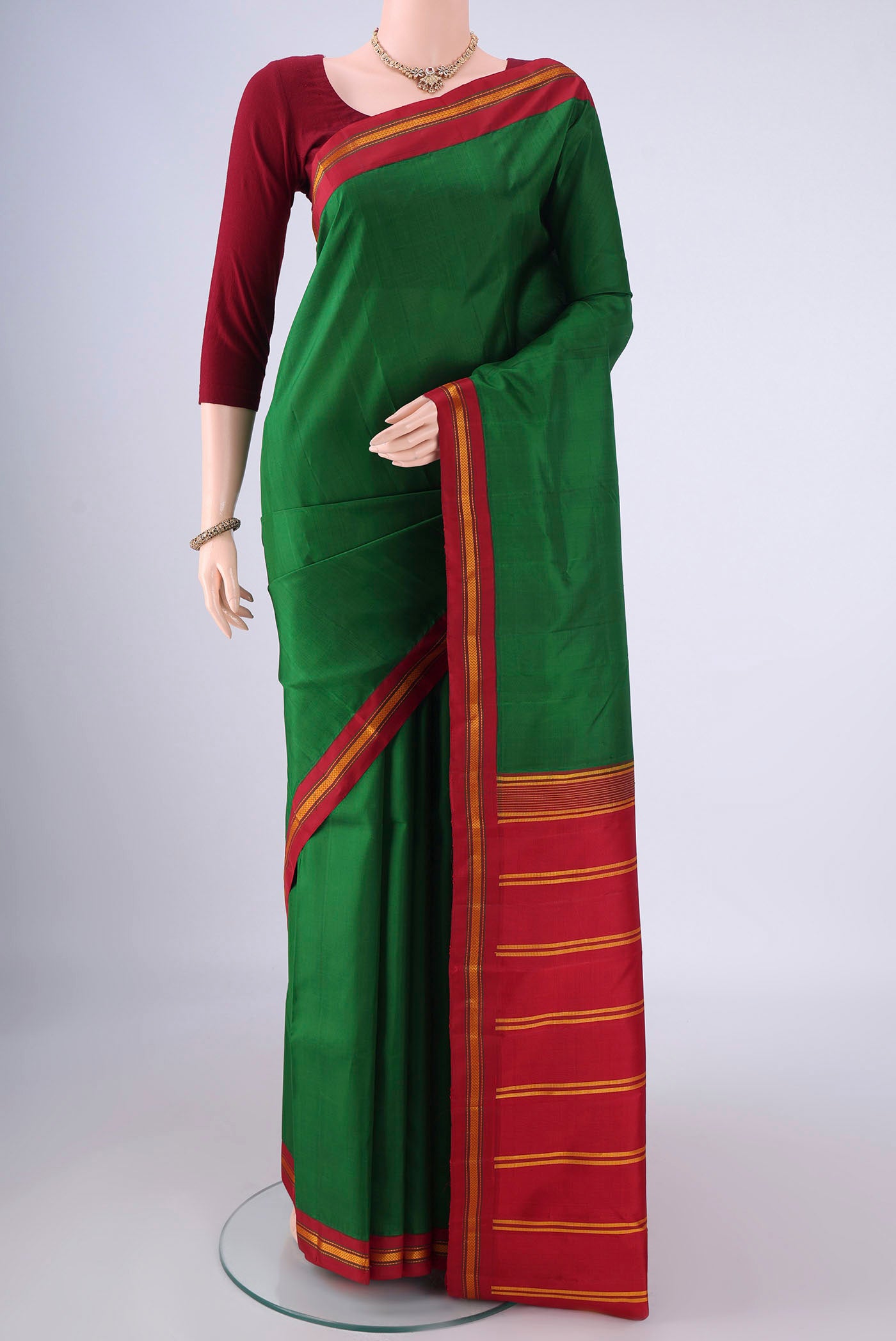 Green Kanjivaram Silk Saree with Plain Body and Thread Border.  displayed on a mannequin