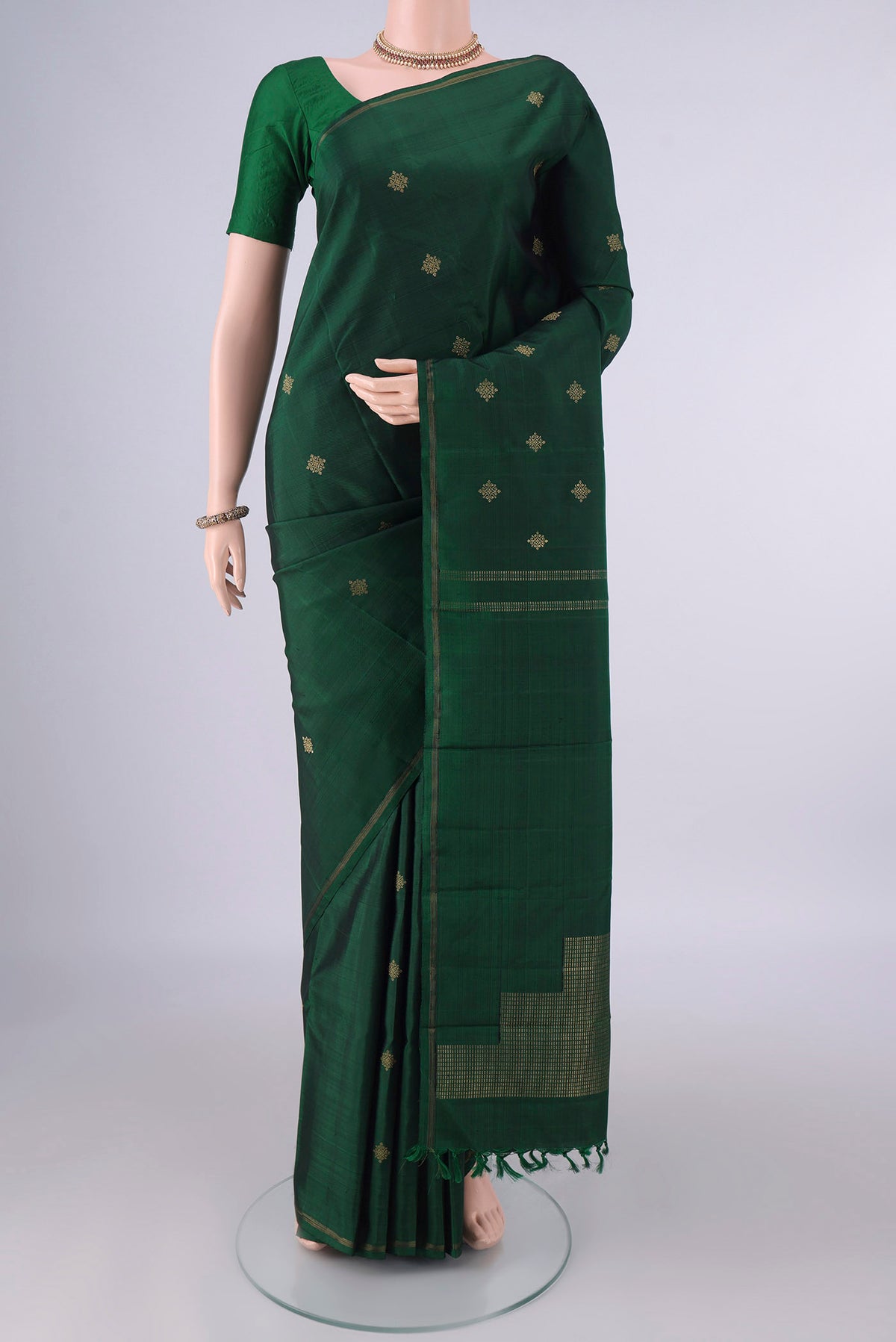 Pure Silk Bottle Green Kanchipuram Saree with Zari Butta on the body and Thin Zari Line.  displayed on a mannequin