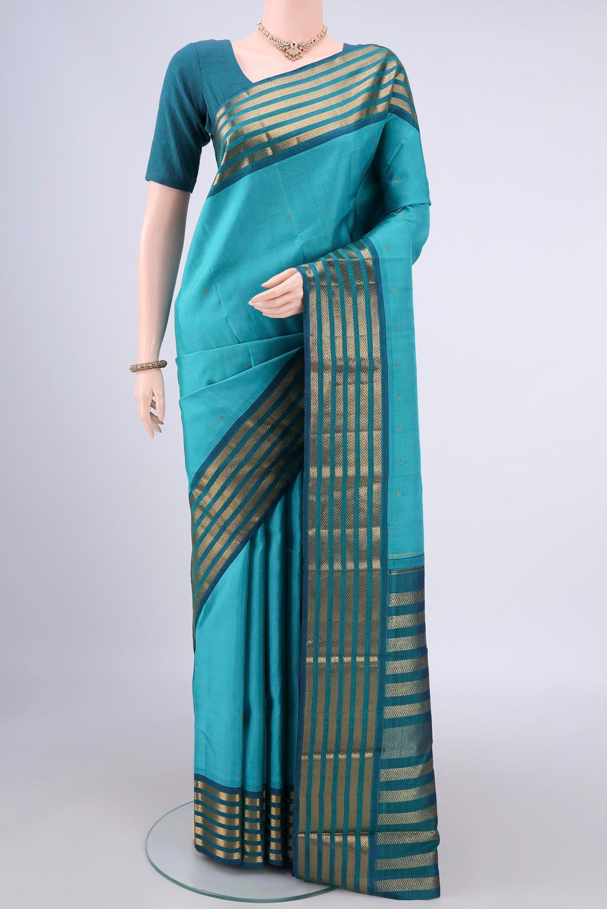 Pure Silk Pure Zari Turquoise Kanjivaram Saree with Zari Butta on the body and Zari Border.  displayed on a mannequin