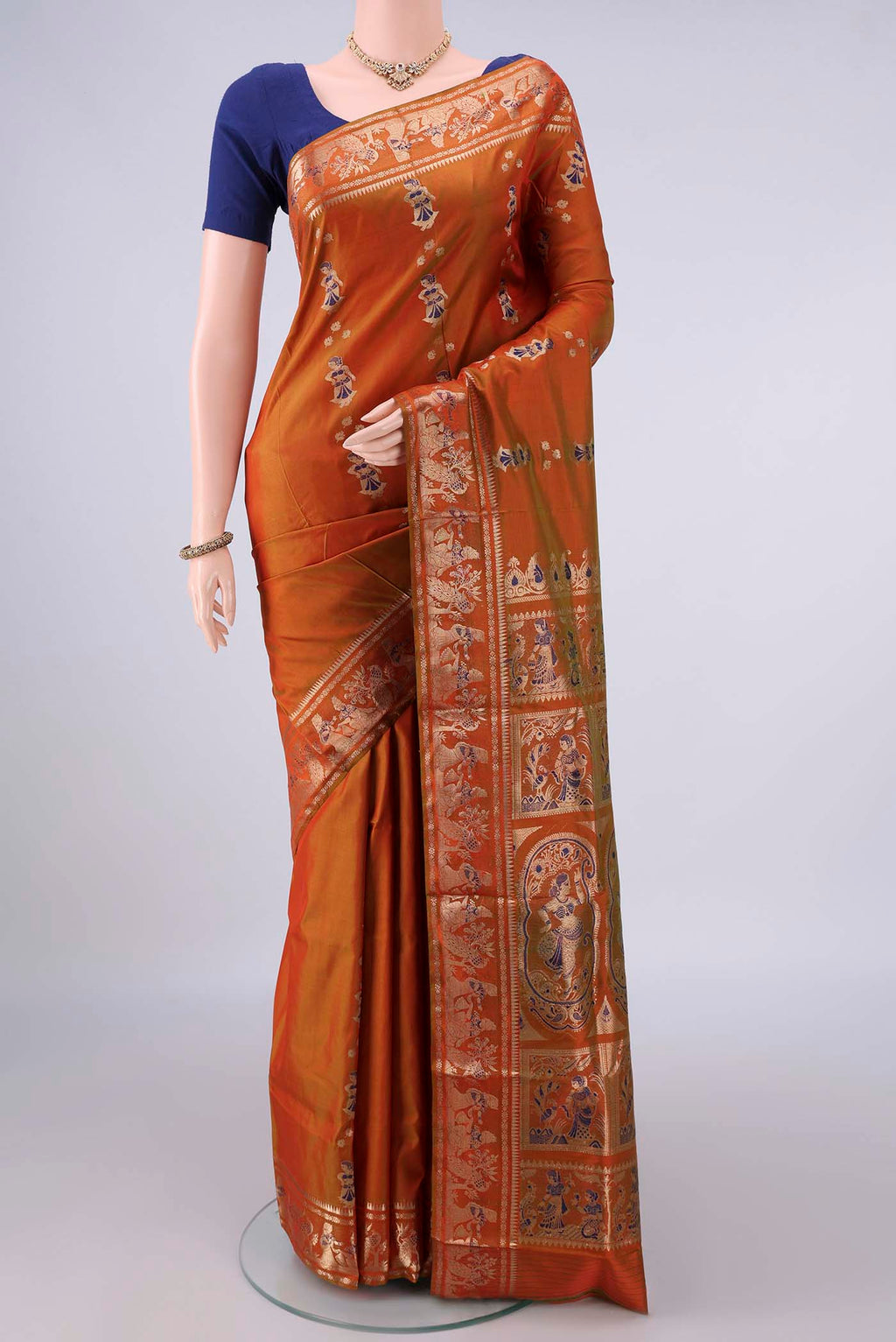 Pure Silk Brick Orange Baluchari Saree with Zari And Thread Butta on the body and Zari Border.  displayed on a mannequin