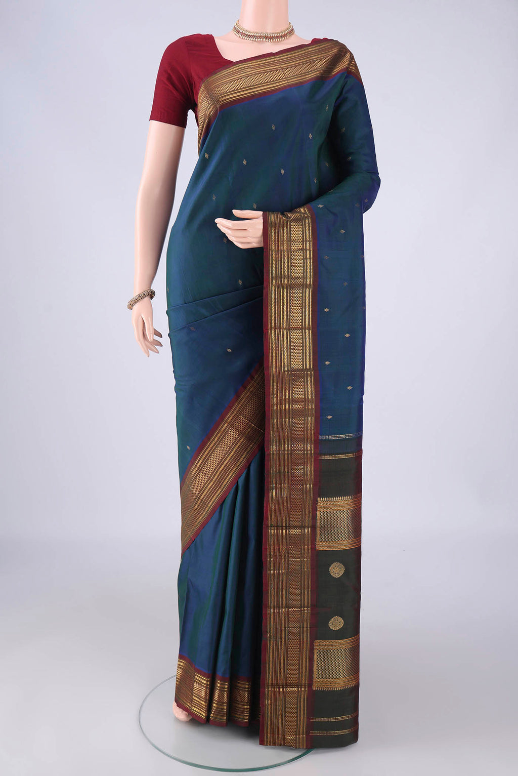 Pure Silk Peacock Blue Kanchipuram Silk Saree with Zari Butta on the body and Zari Border.  displayed on a mannequin