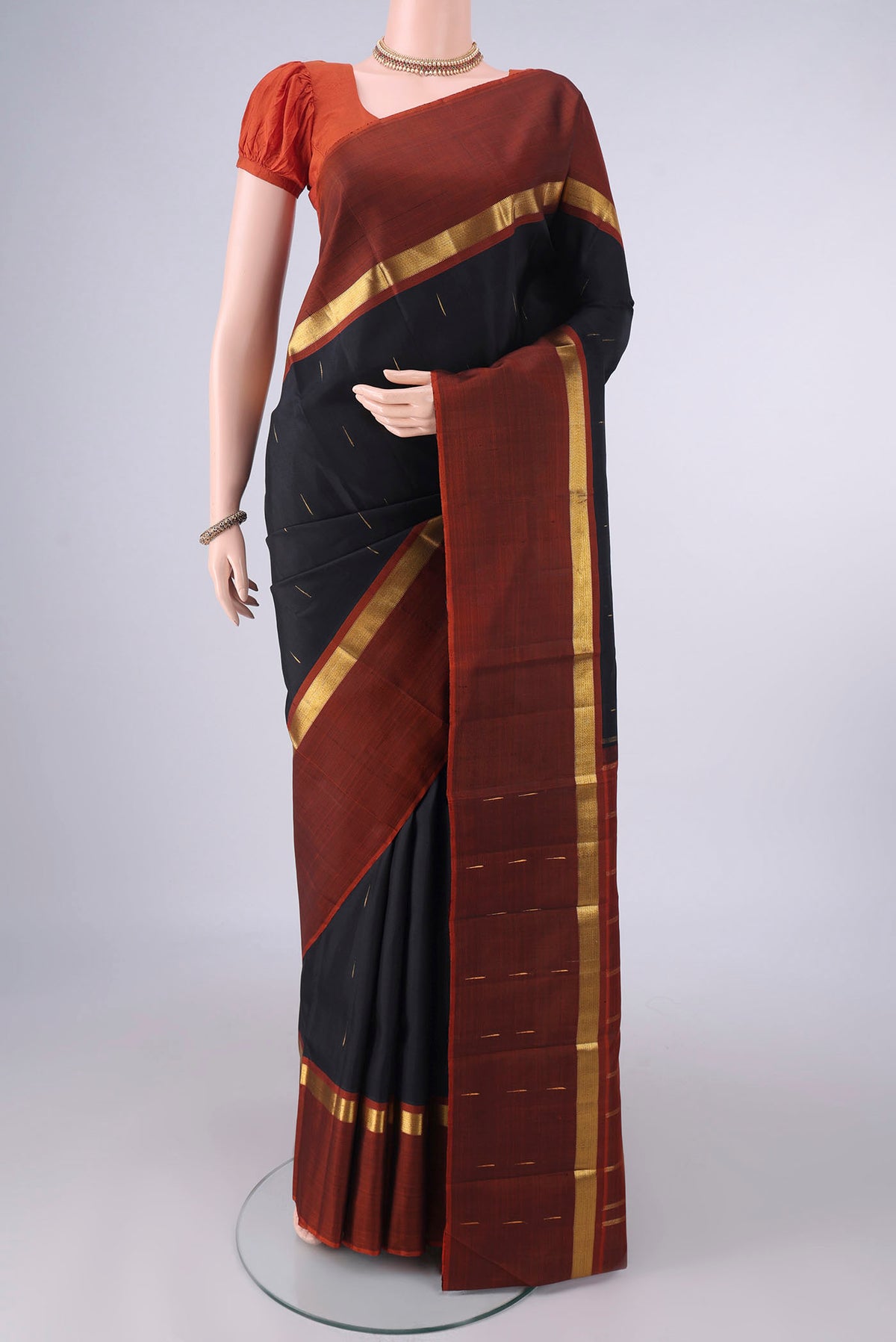 Pure Silk Black Kanjivaram Saree with Zari Butta on the body and Zari Border.  displayed on a mannequin