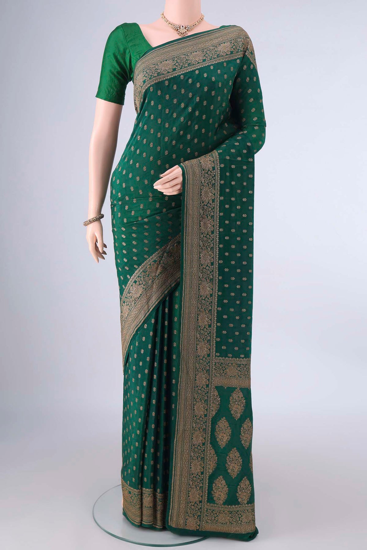 Bottle Green Banarasi Georgette Saree with Zari Butta on the body and Zari Border.  displayed on a mannequin
