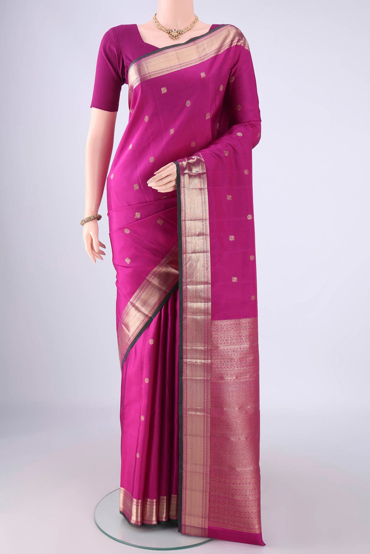 Magenta Kanjivaram Silk Saree with Zari Butta on the body and Zari Border.  displayed on a mannequin