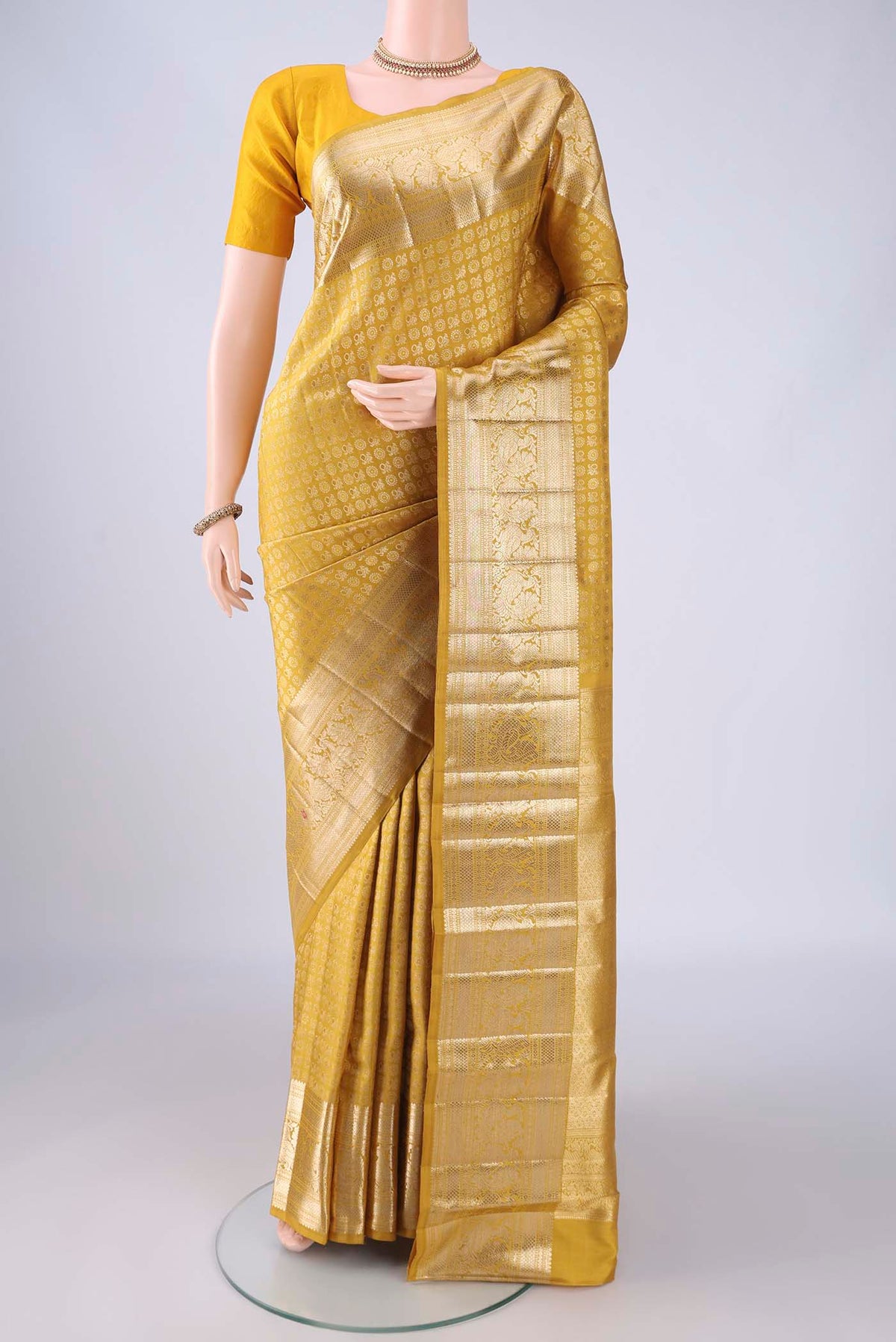 Mustard Kanchipuram Silk Saree with Zari Brocade on the body and Zari Border.  displayed on a mannequin