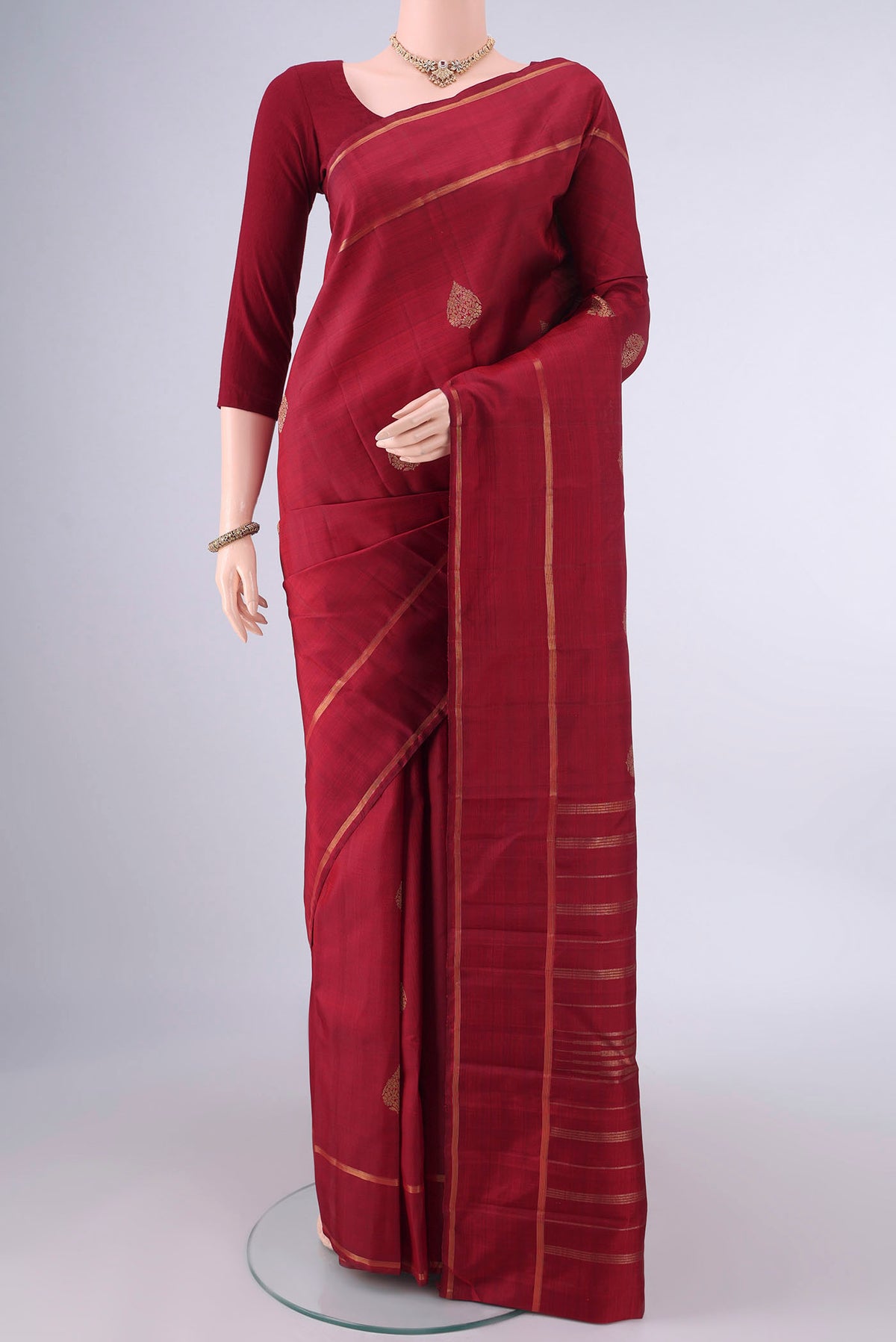 Pure Silk Maroon Kanjivaram Saree with Zari Butta on the body and Zari Border.  displayed on a mannequin