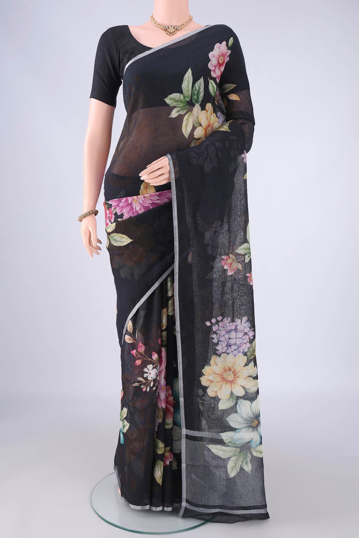 Black Linen Saree with Floral Print on the body and Zari Border.  displayed on a mannequin
