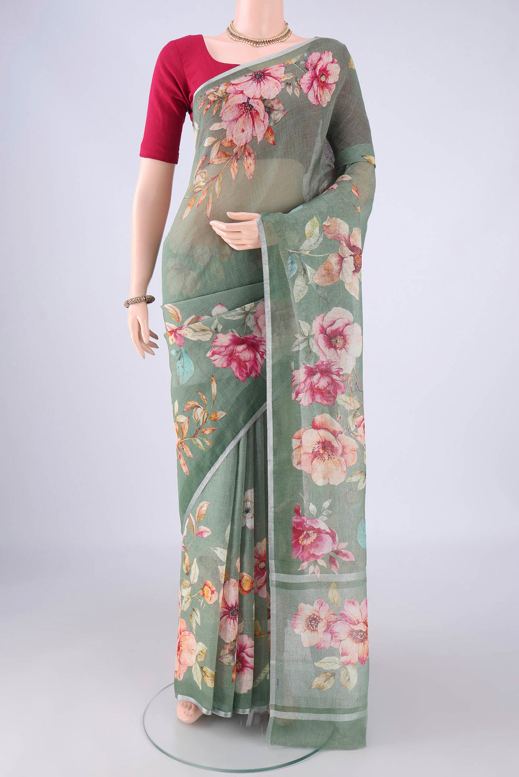 Sage Green Linen Saree with Floral Print on the body and Zari Border.  displayed on a mannequin