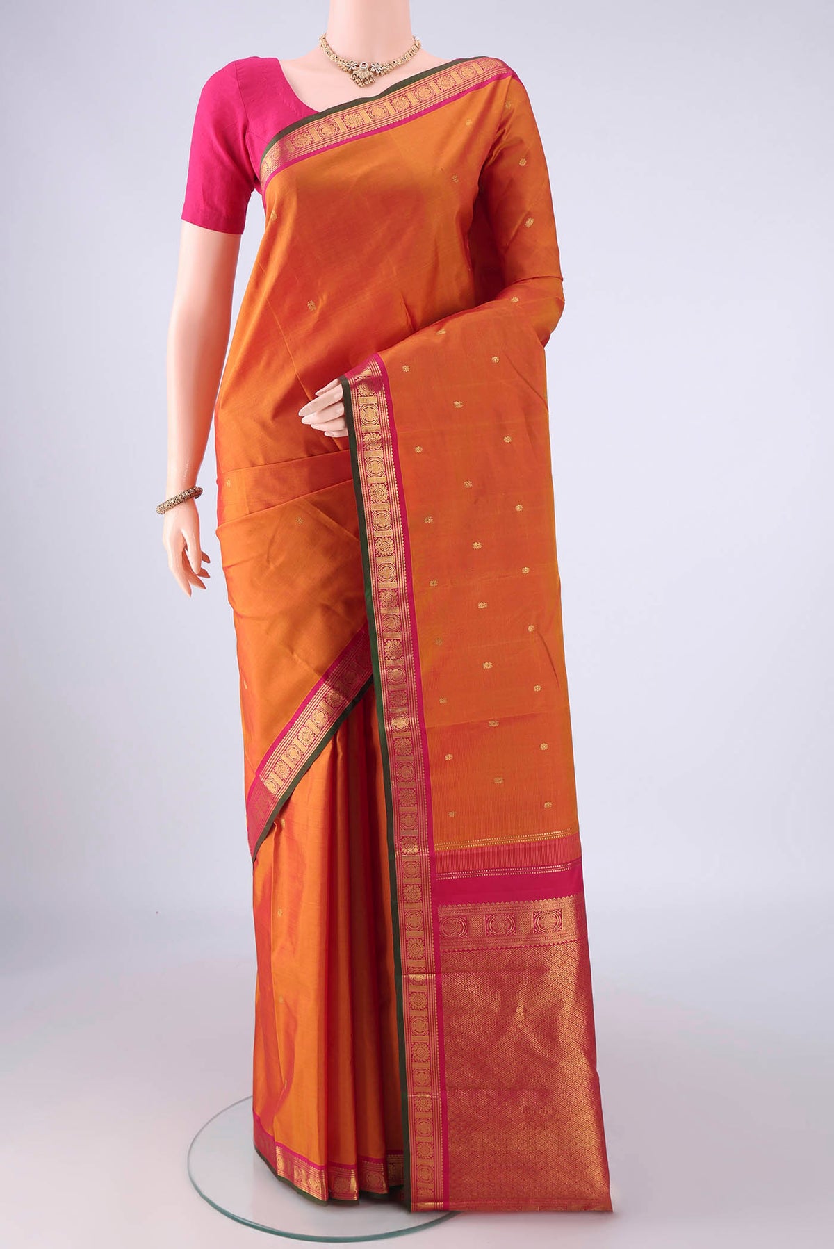 Brick Orange Kanjivaram Silk Saree with Zari Butta on the body and Zari Border.  displayed on a mannequin