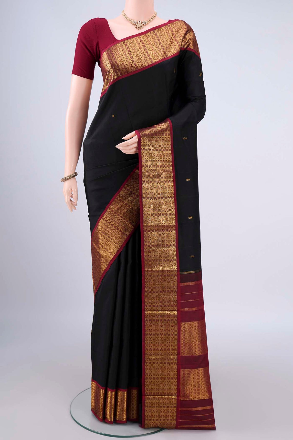 Pure Silk Black Kanjivaram Saree with Zari Butta on the body and Zari Border.  displayed on a mannequin