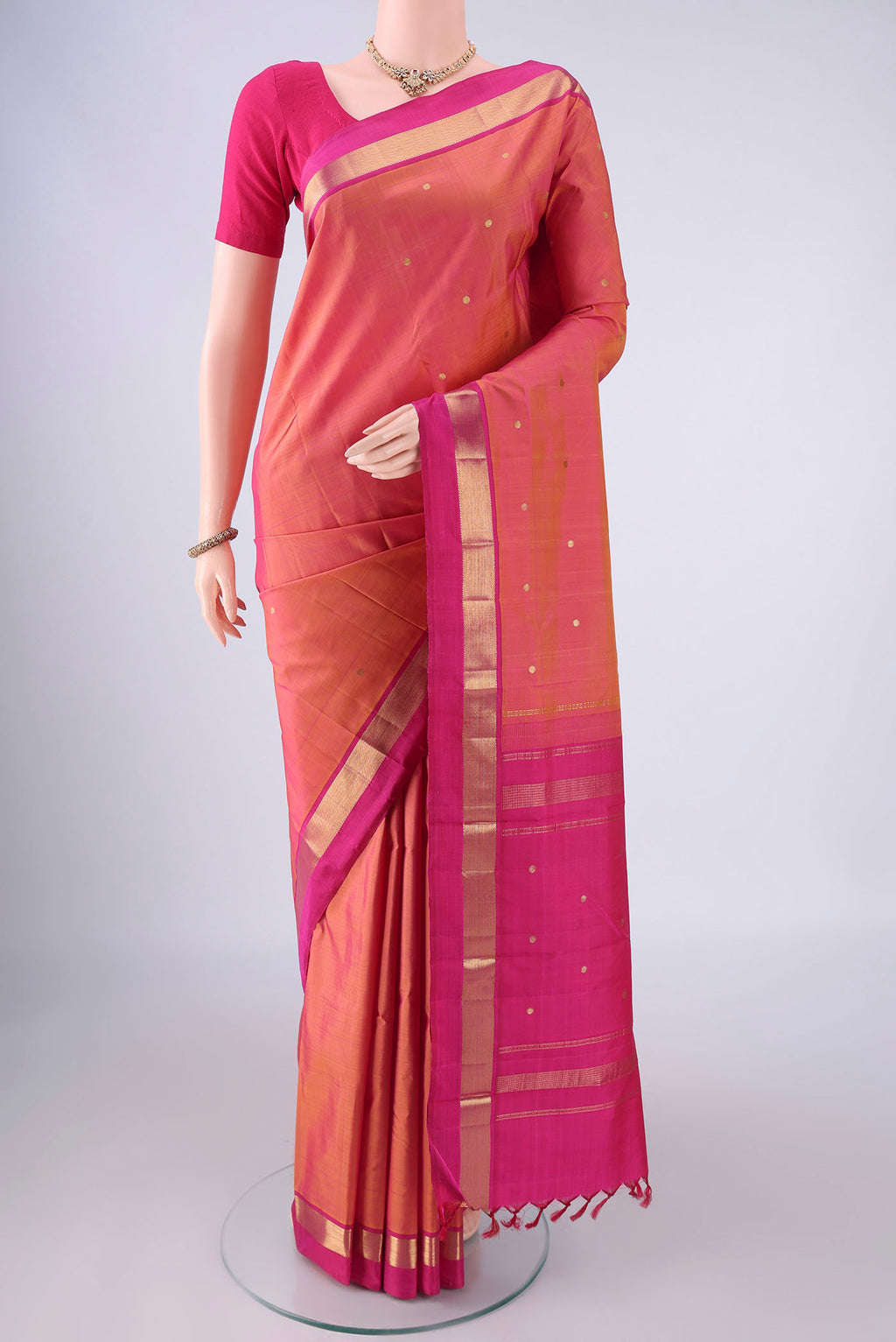 Pinkish Yellow Dual Tone Kanjivaram Silk Saree with Zari Butta on the body and Zari Border.  displayed on a mannequin