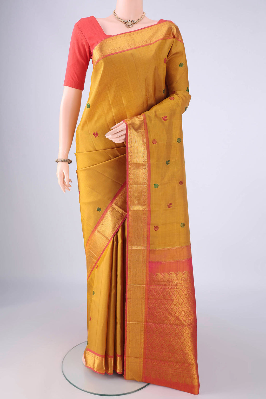 Mustard Kanchipuram Silk Saree with Thread Butta on the body and Zari Border.  displayed on a mannequin