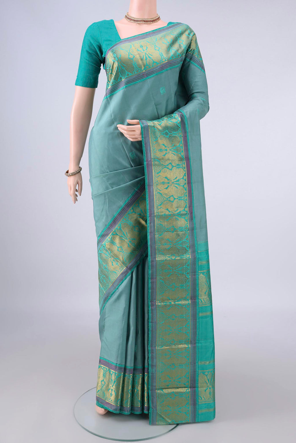Pure Silk Sage Green Kanchipuram Saree with Thread Butta on the body and Zari And Thread Border.  displayed on a mannequin