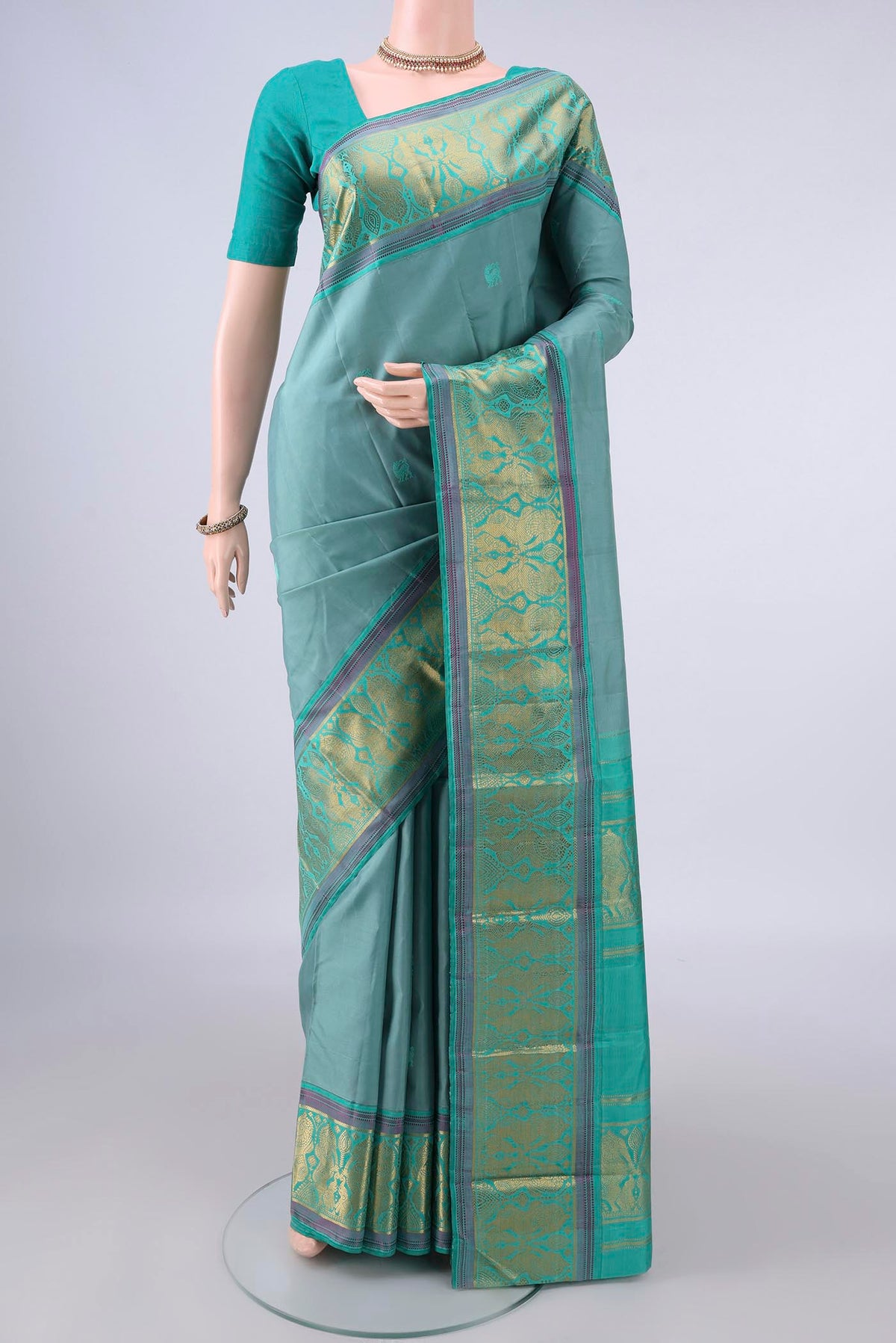 Pure Silk Sage Green Kanchipuram Saree with Thread Butta on the body and Zari And Thread Border.  displayed on a mannequin