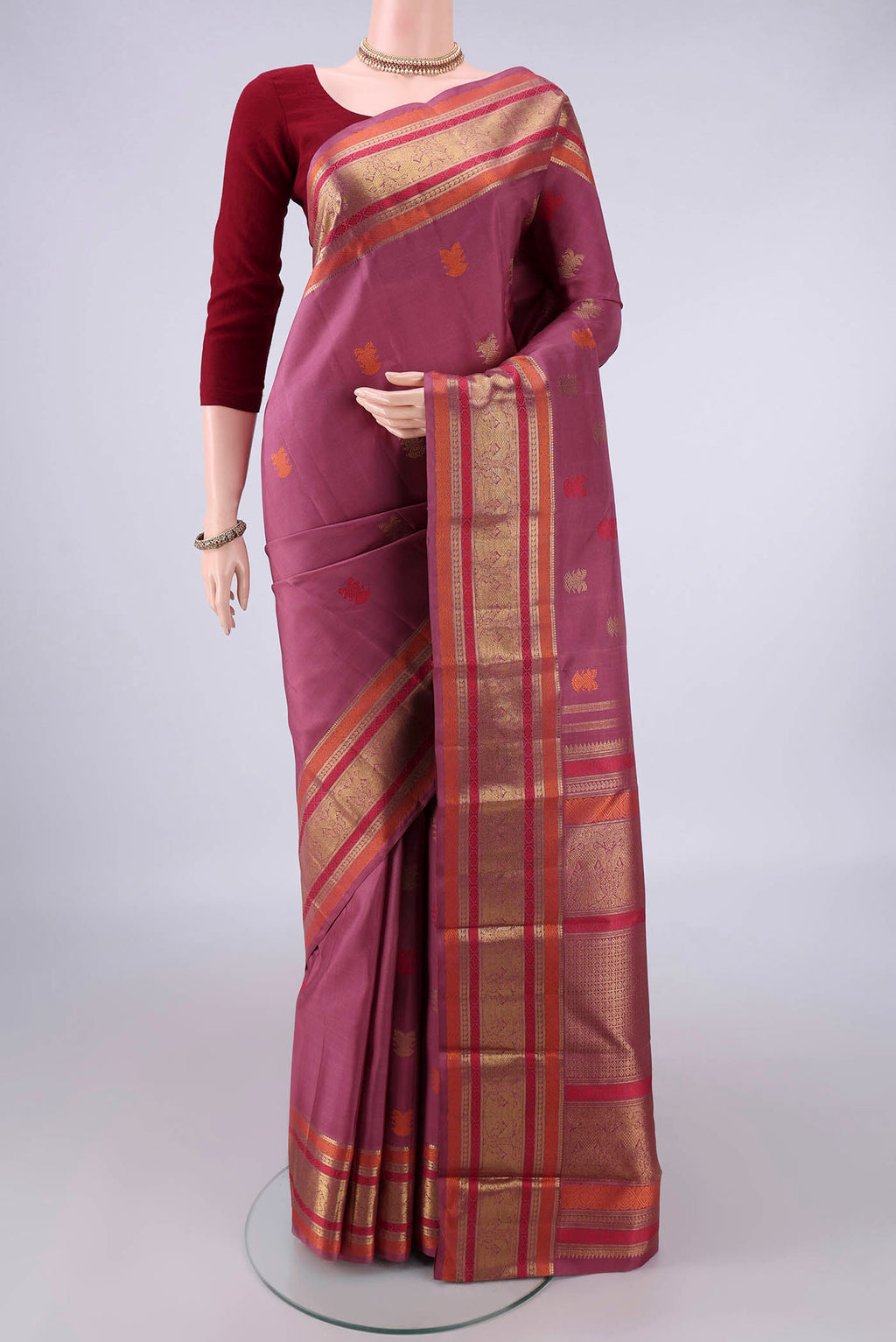 Pure Silk Pure Zari Mauve Kanjivaram Saree with Zari And Thread Butta on the body and Zari And Thread Border.  displayed on a mannequin