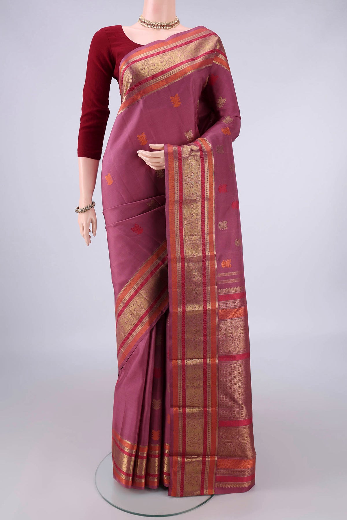 Pure Silk Pure Zari Mauve Kanjivaram Saree with Zari And Thread Butta on the body and Zari And Thread Border.  displayed on a mannequin