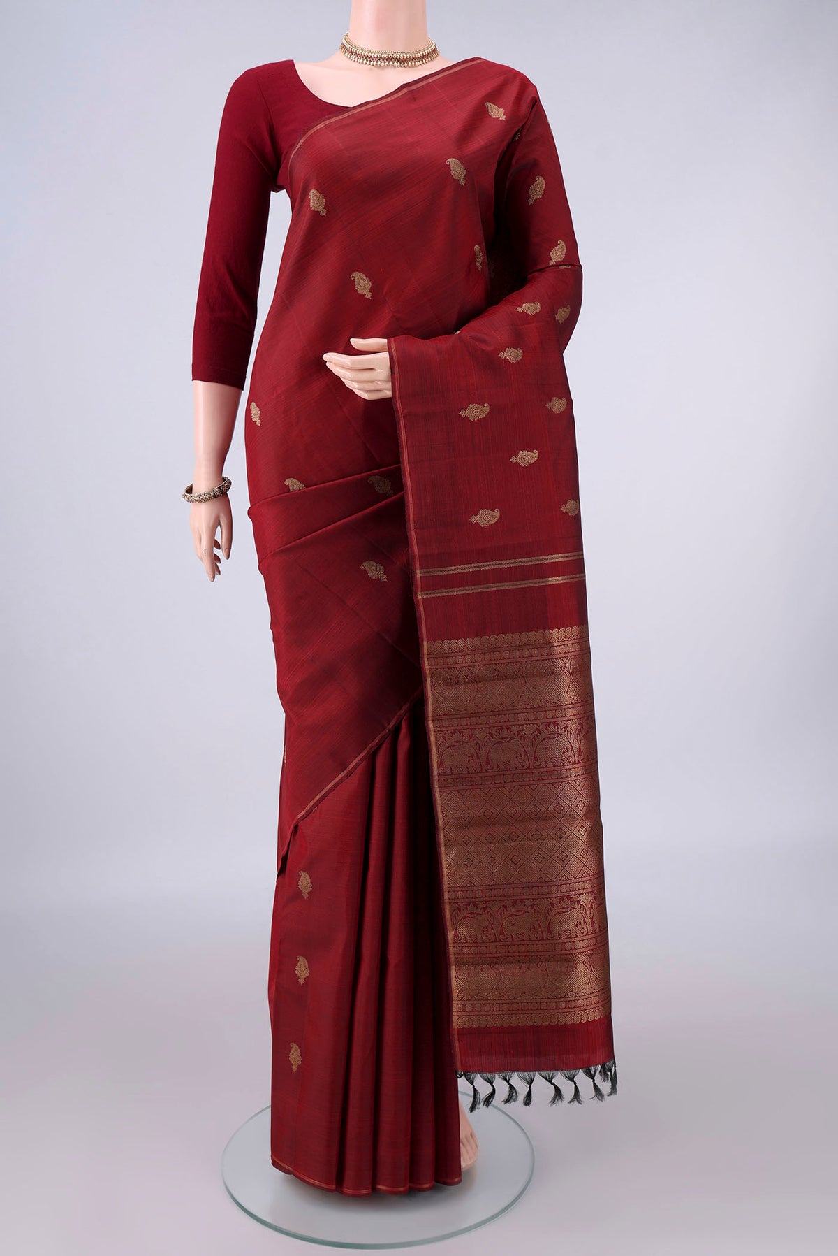 Pure Silk Pure Zari Maroon Kanchipuram Saree with Zari Butta on the body and Thin Zari Line.  displayed on a mannequin