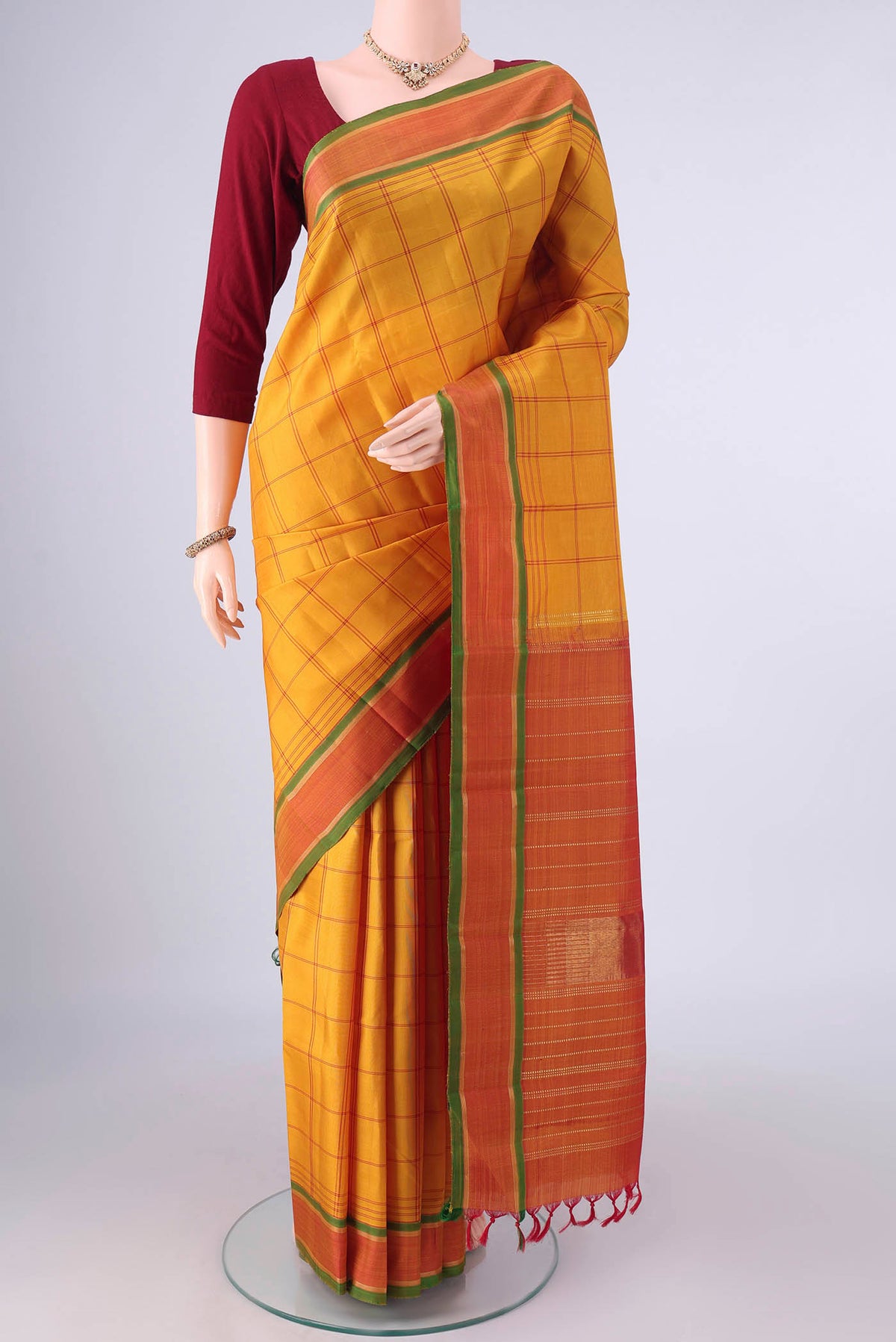 Pure Silk Mustard Kanjivaram Saree with Checked design on the body and Zari Border.  displayed on a mannequin