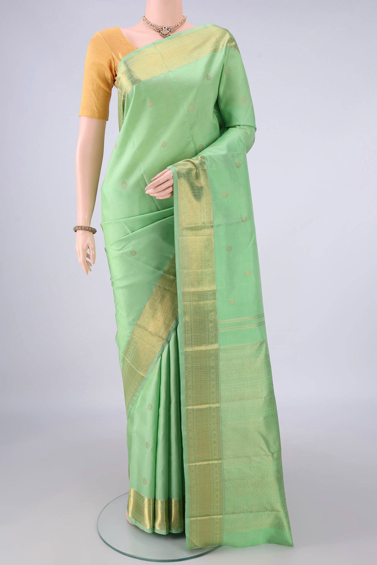 Pure Silk Pure Zari Pista Green Kanjivaram Saree with Zari Butta on the body and Zari Border.  displayed on a mannequin