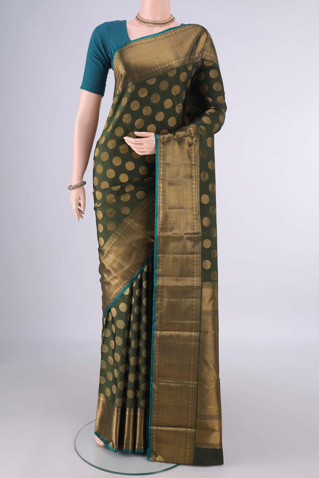 Pure Silk Olive Green Kanchipuram Saree with Thread Butta on the body and Zari Border.  displayed on a mannequin