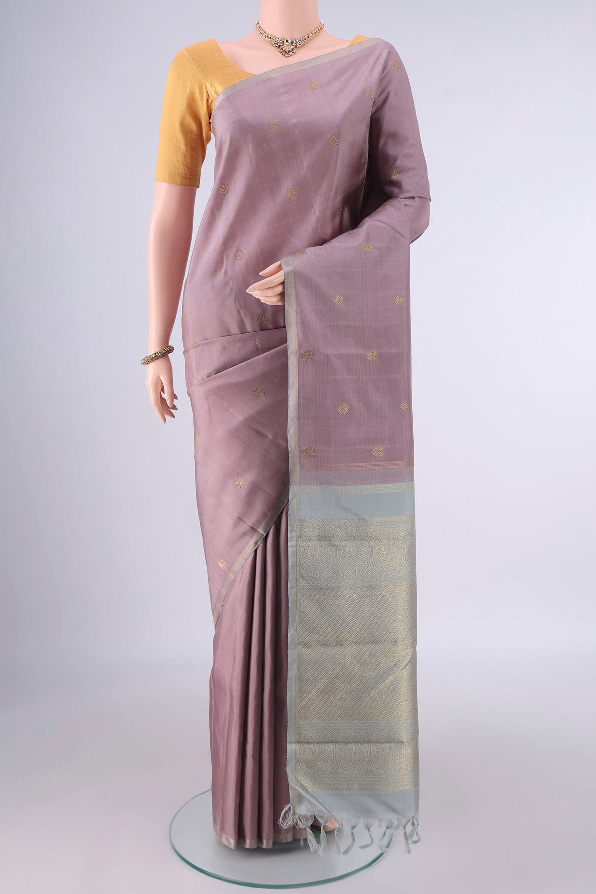 Pure Silk Rose Gold Kanchipuram Saree with Zari Butta on the body and Thin Zari Line.  displayed on a mannequin
