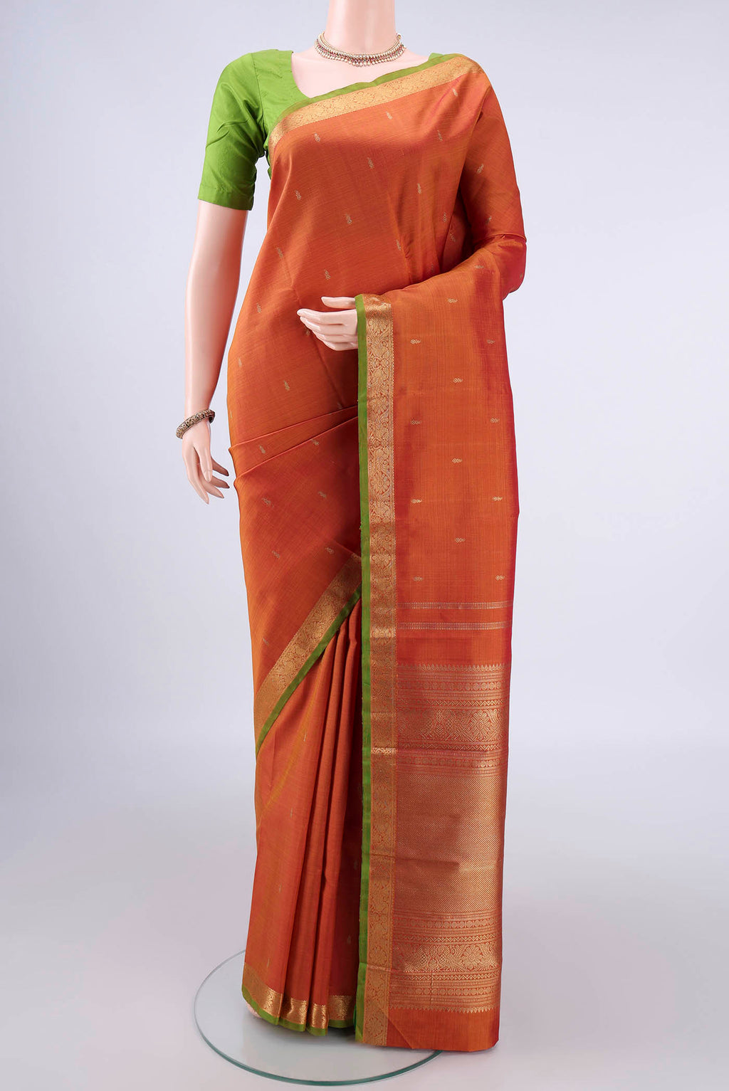 Pure Silk Pure Zari Brick Orange Kanchipuram Saree with Zari Butta on the body and Zari Border.  displayed on a mannequin