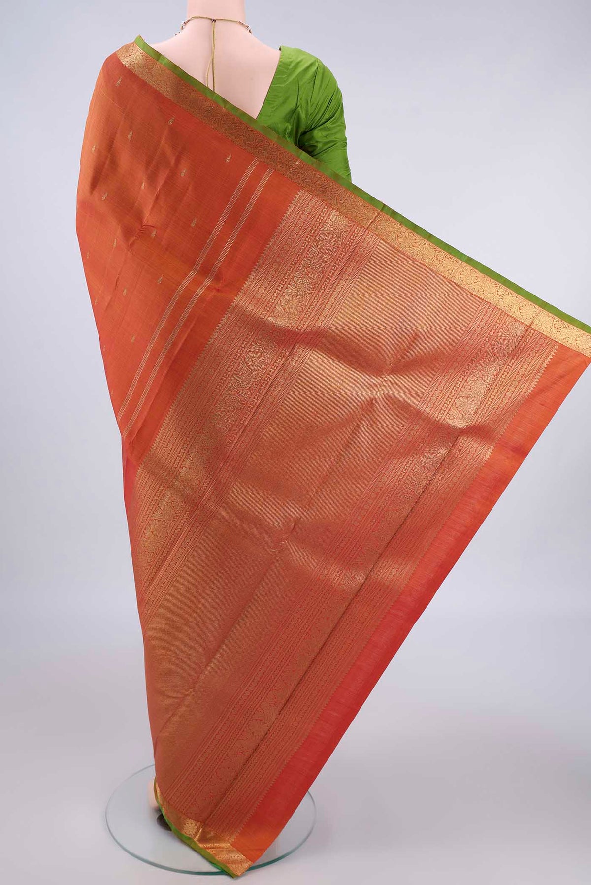 Flat view of Pure Silk Pure Zari Brick Orange Kanchipuram Saree with Zari Butta on the body and Zari Border. 