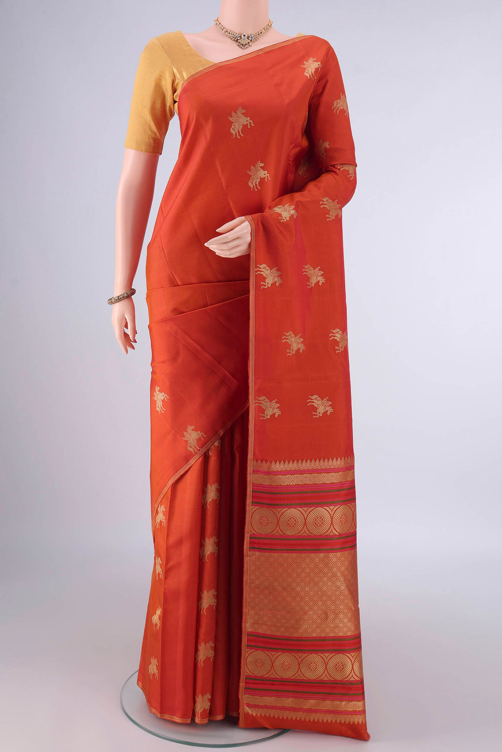 Pure Silk Rust Kanjivaram Saree with Thread Butta on the body and Thin Zari Line.  displayed on a mannequin